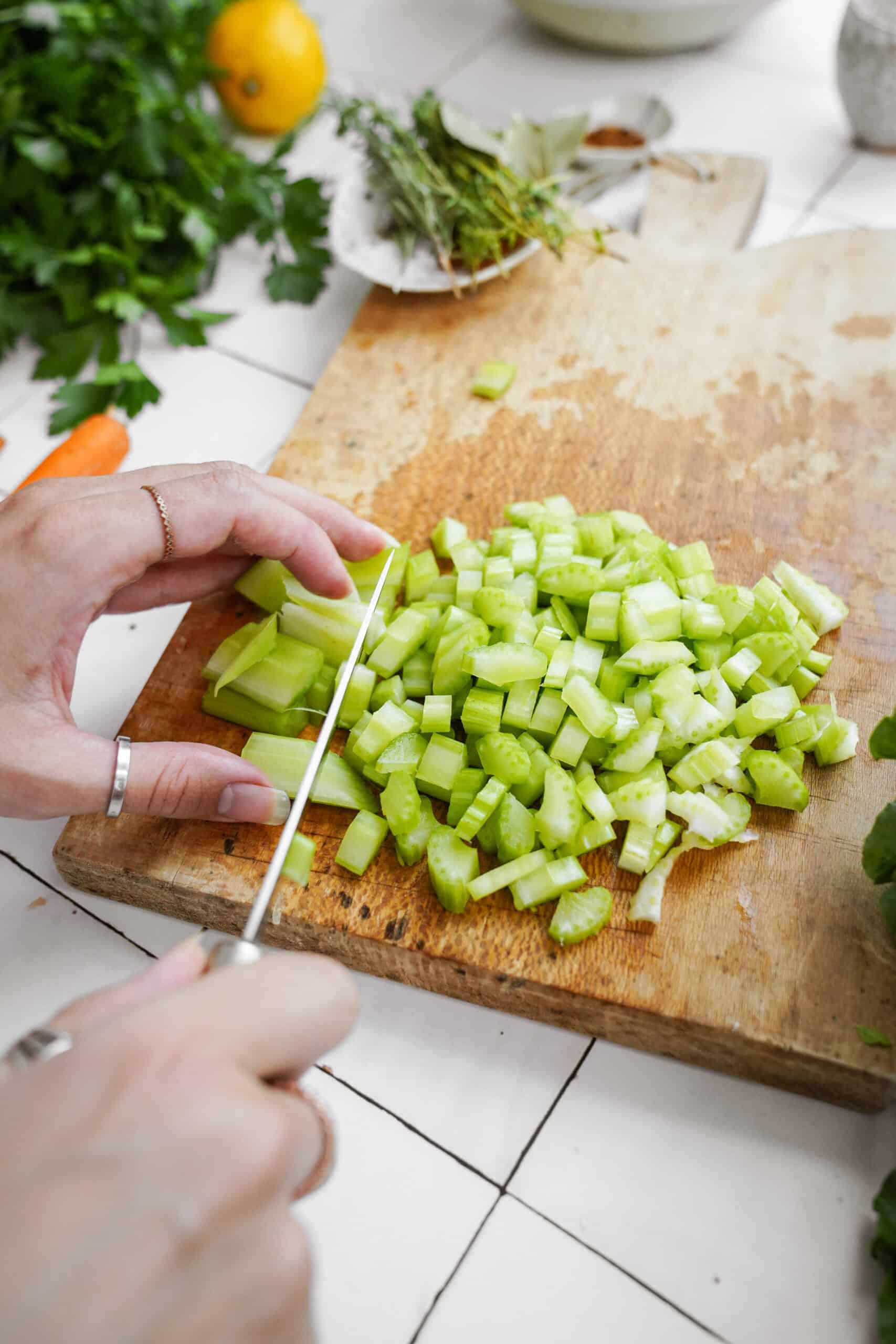 Hands chopping up celery on board