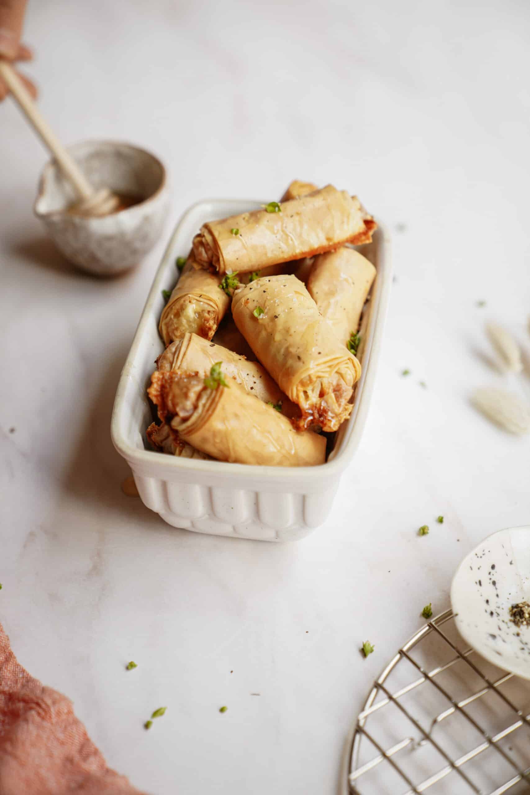 Baked brie bites in a mini white dish with honey being drizzled on