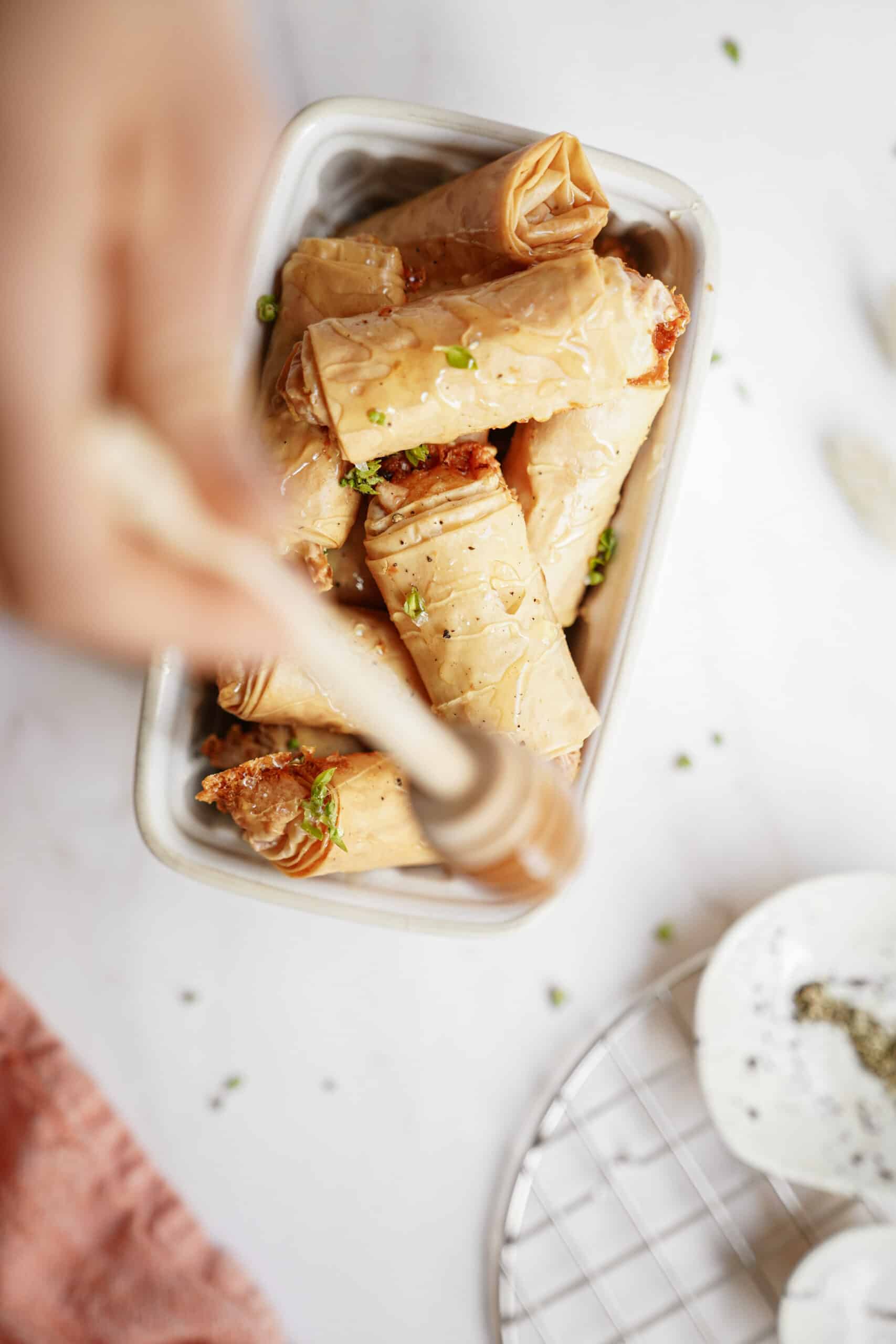 Baked brie bites in a mini white dish with honey being drizzled on