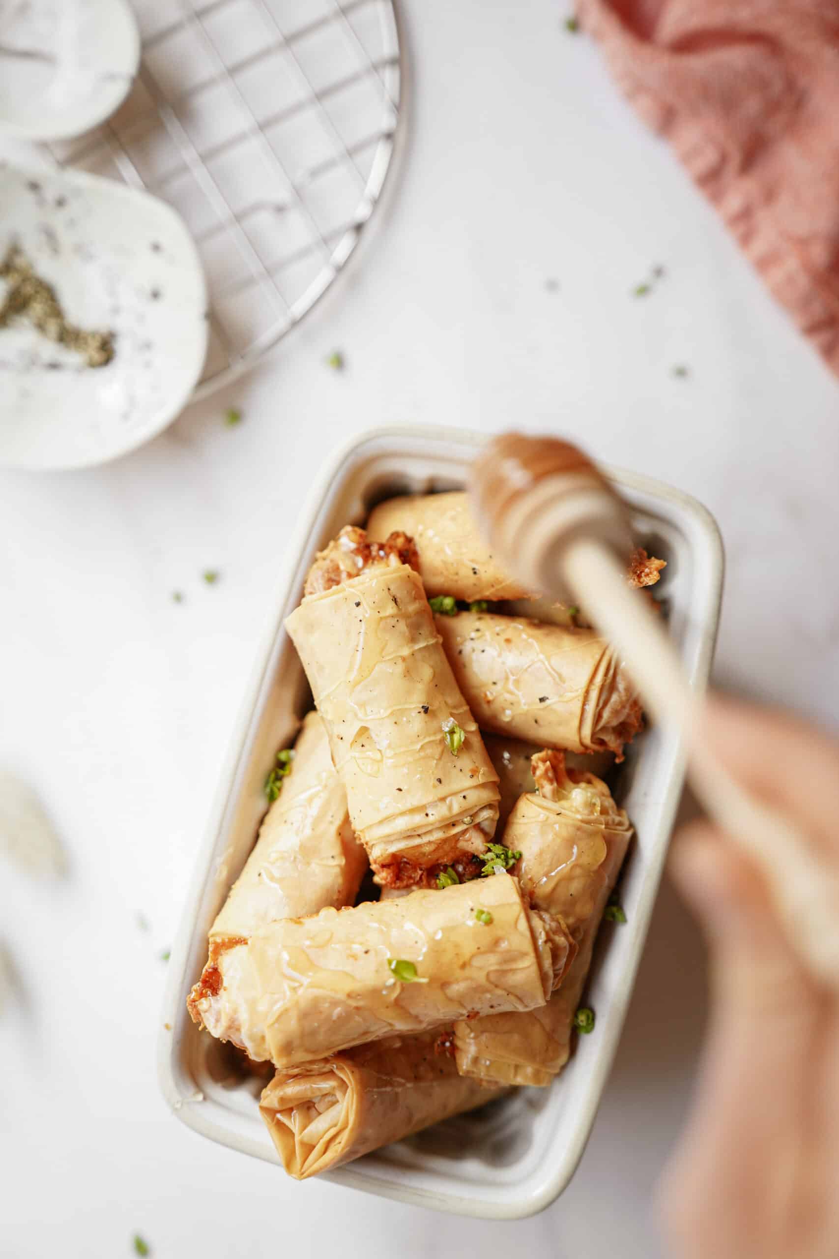 Baked brie bites in a mini white dish with honey being drizzled on