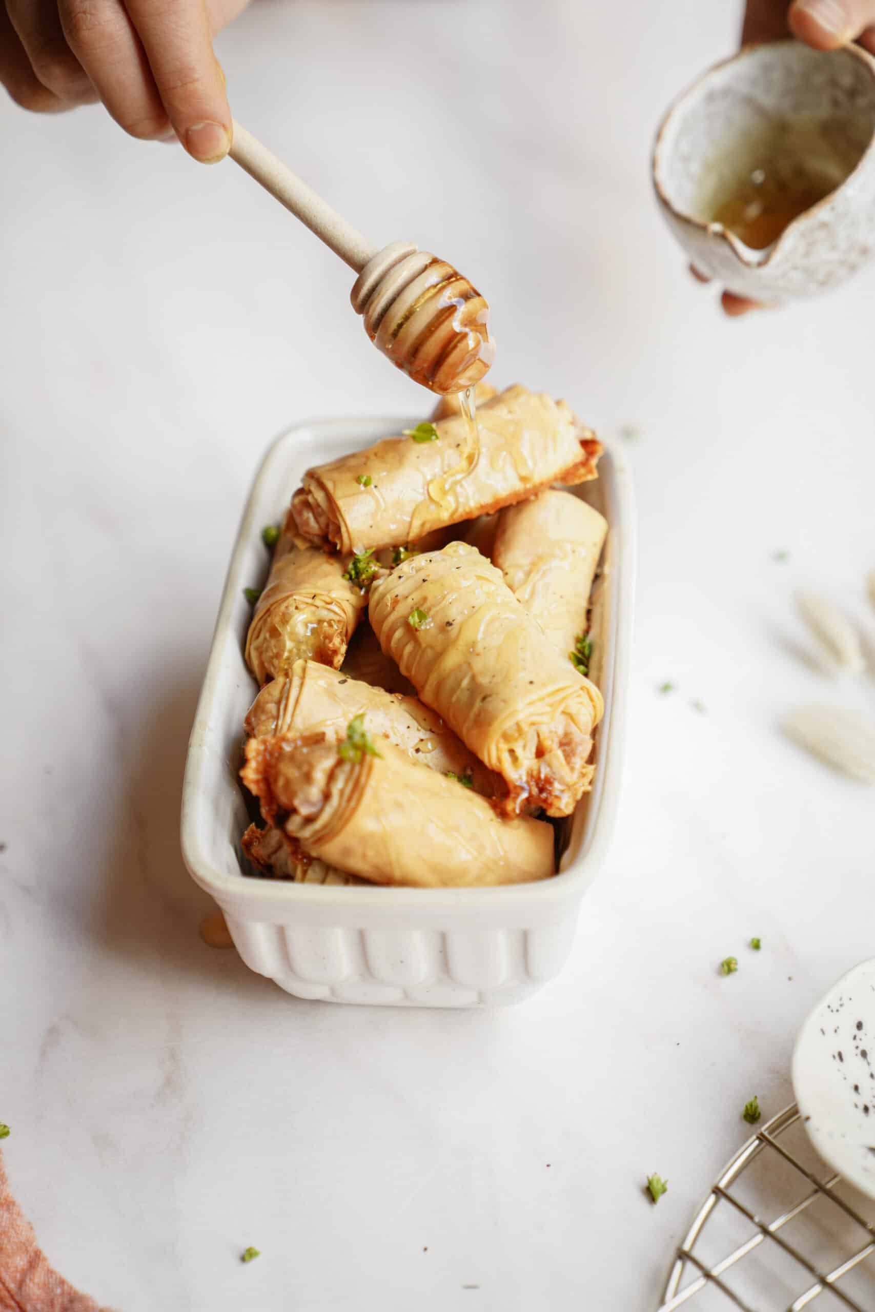 Baked brie bites in a mini white dish with honey being drizzled on
