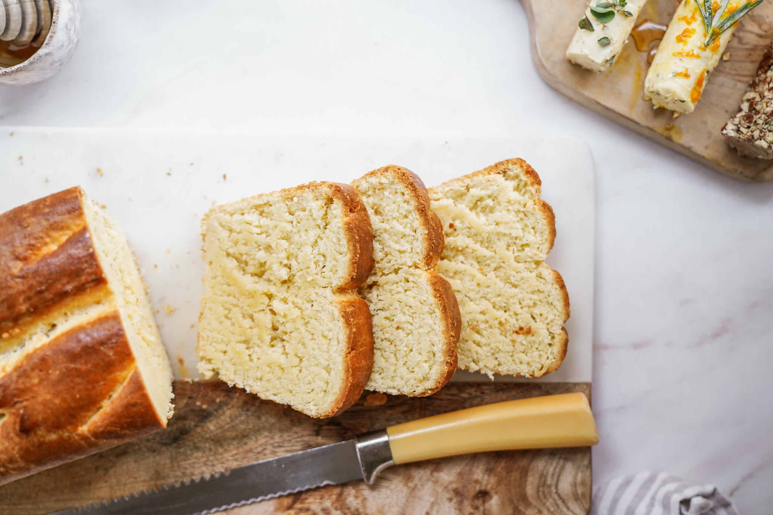 Sliced homemade bread next to compound butter on cutting board