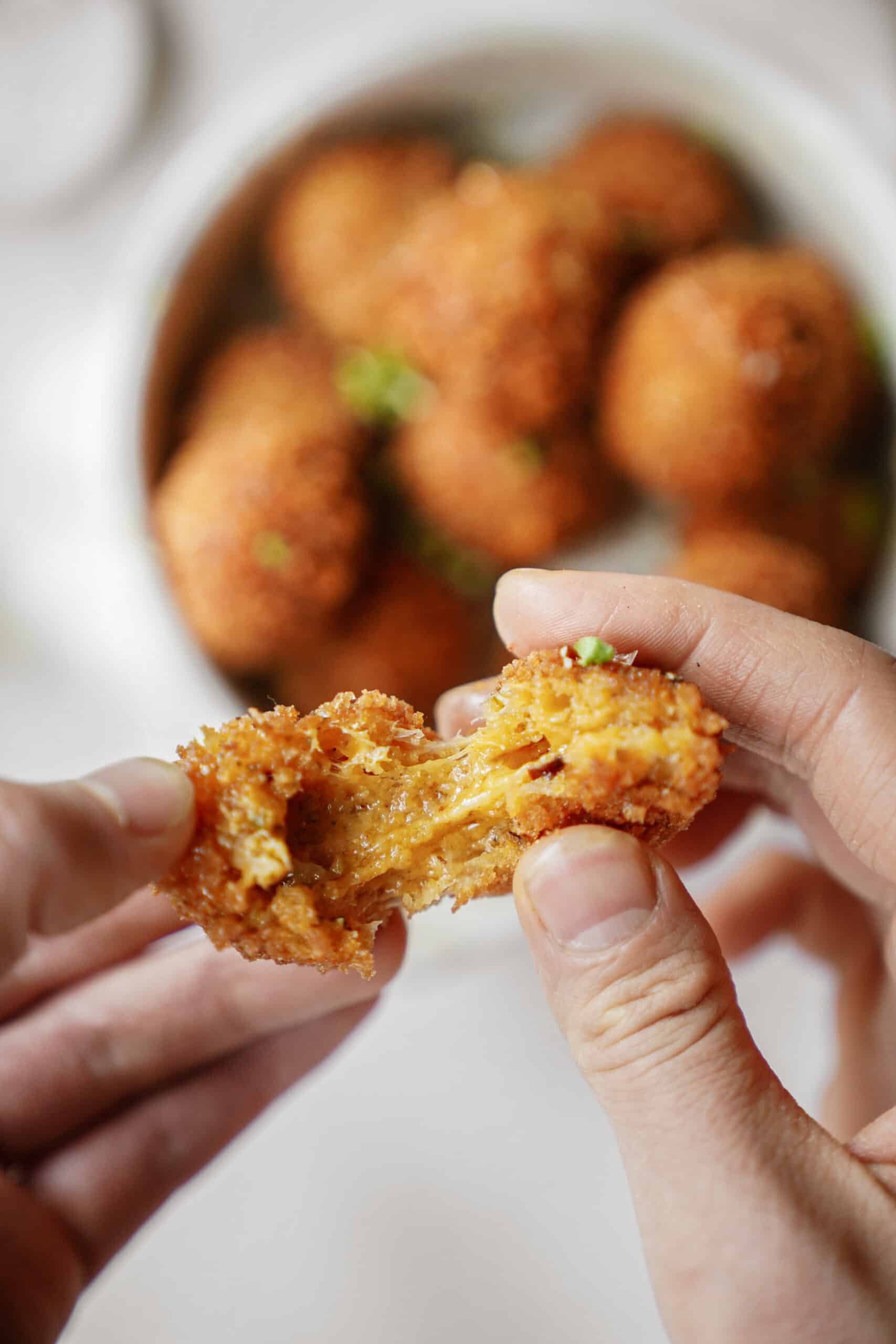 Hands pulling apart a fried cheese ball