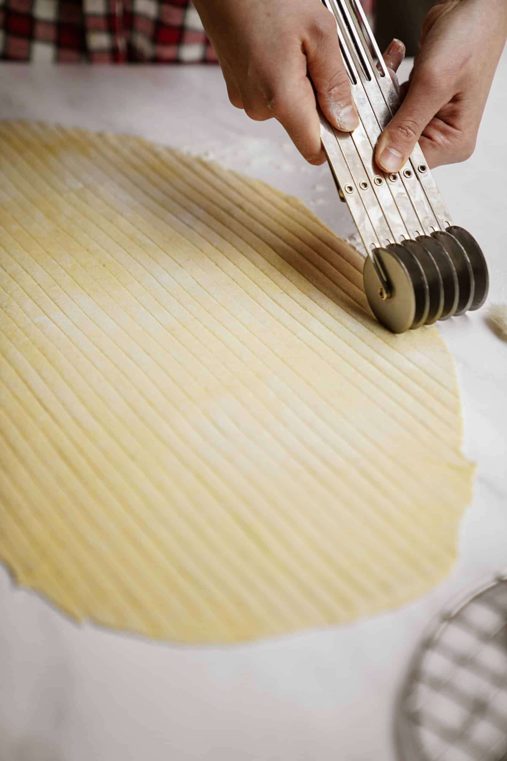 Pasta noodles being cut out of dough