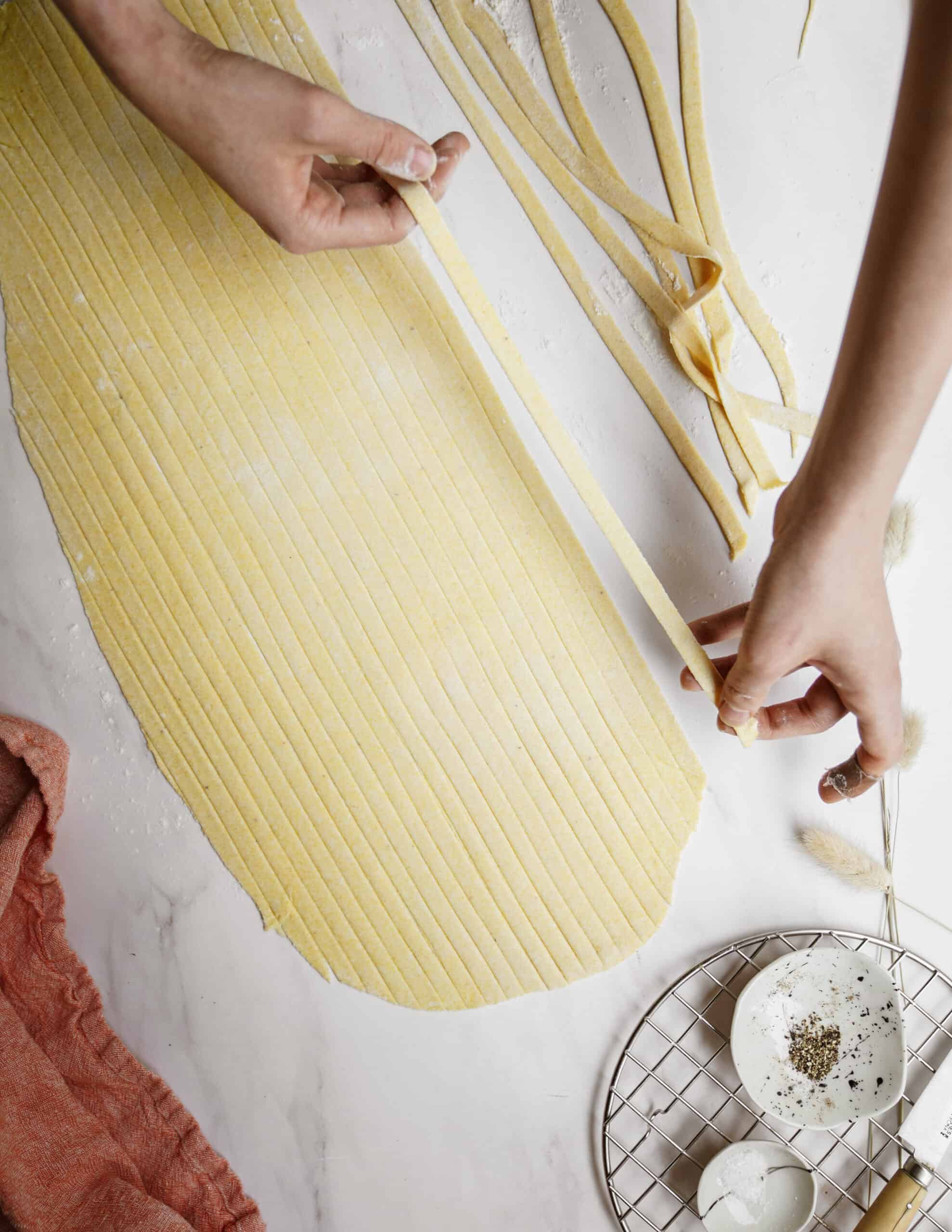 Hands separating pasta from dough