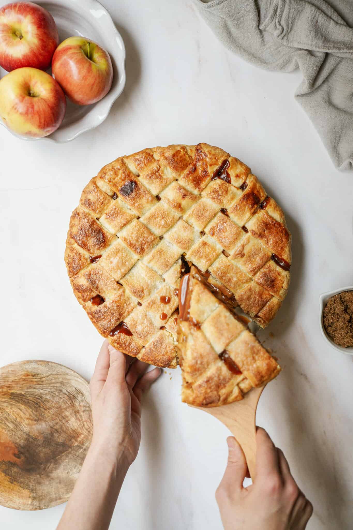Homemade apple pie on counter with slice being taken out