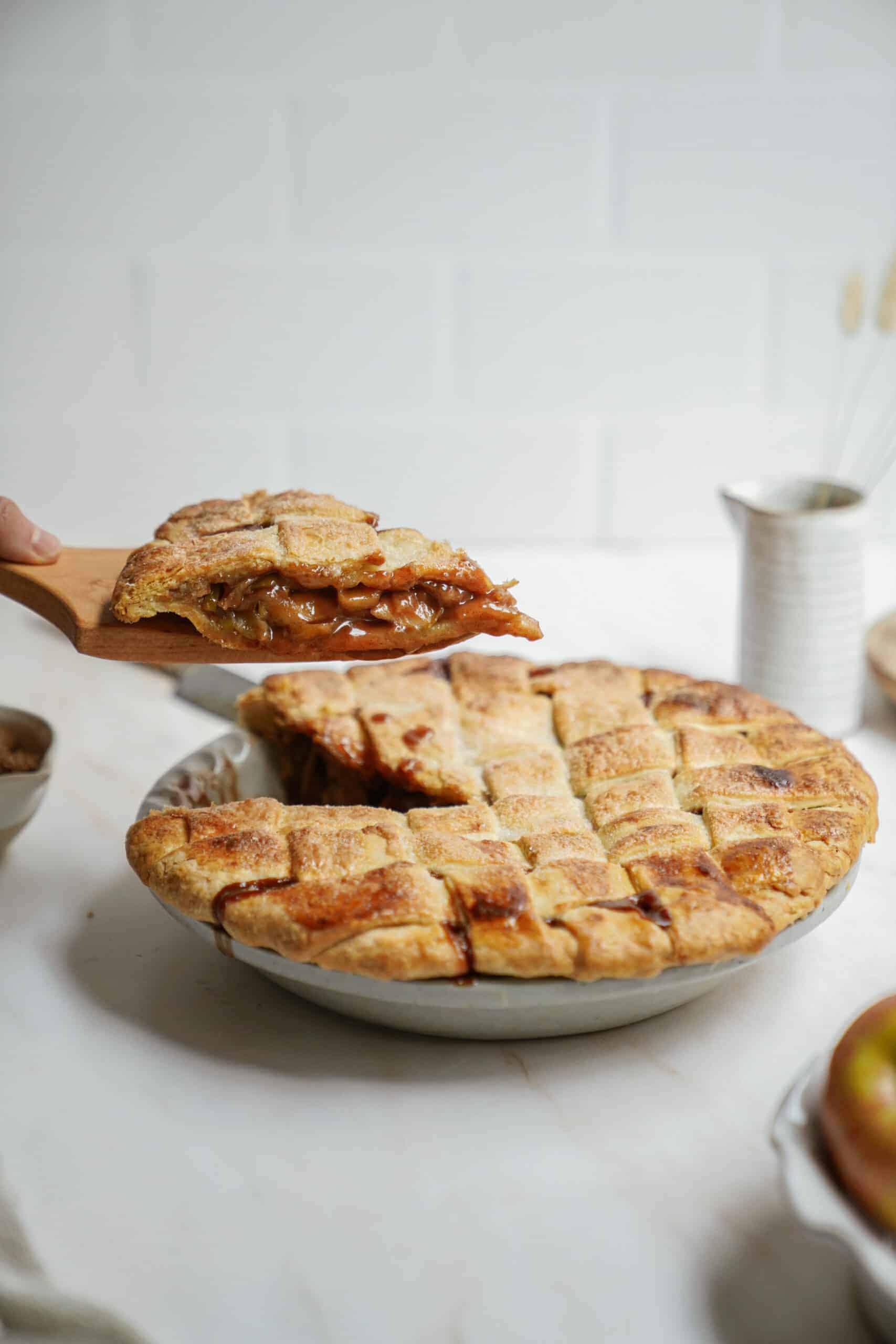Homemade apple pie on counter with slice being taken out