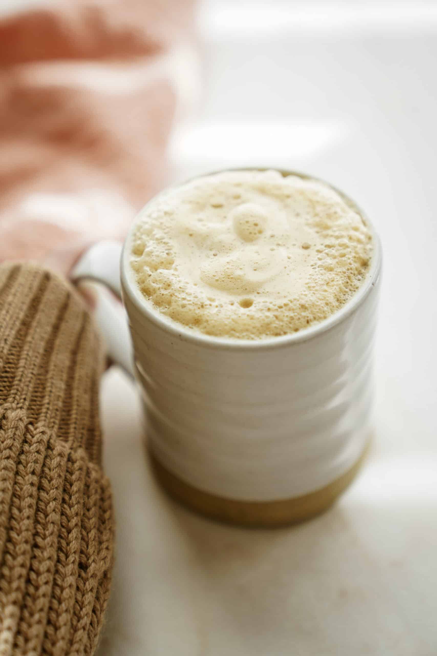Hand holding mug with pumpkin spice latte