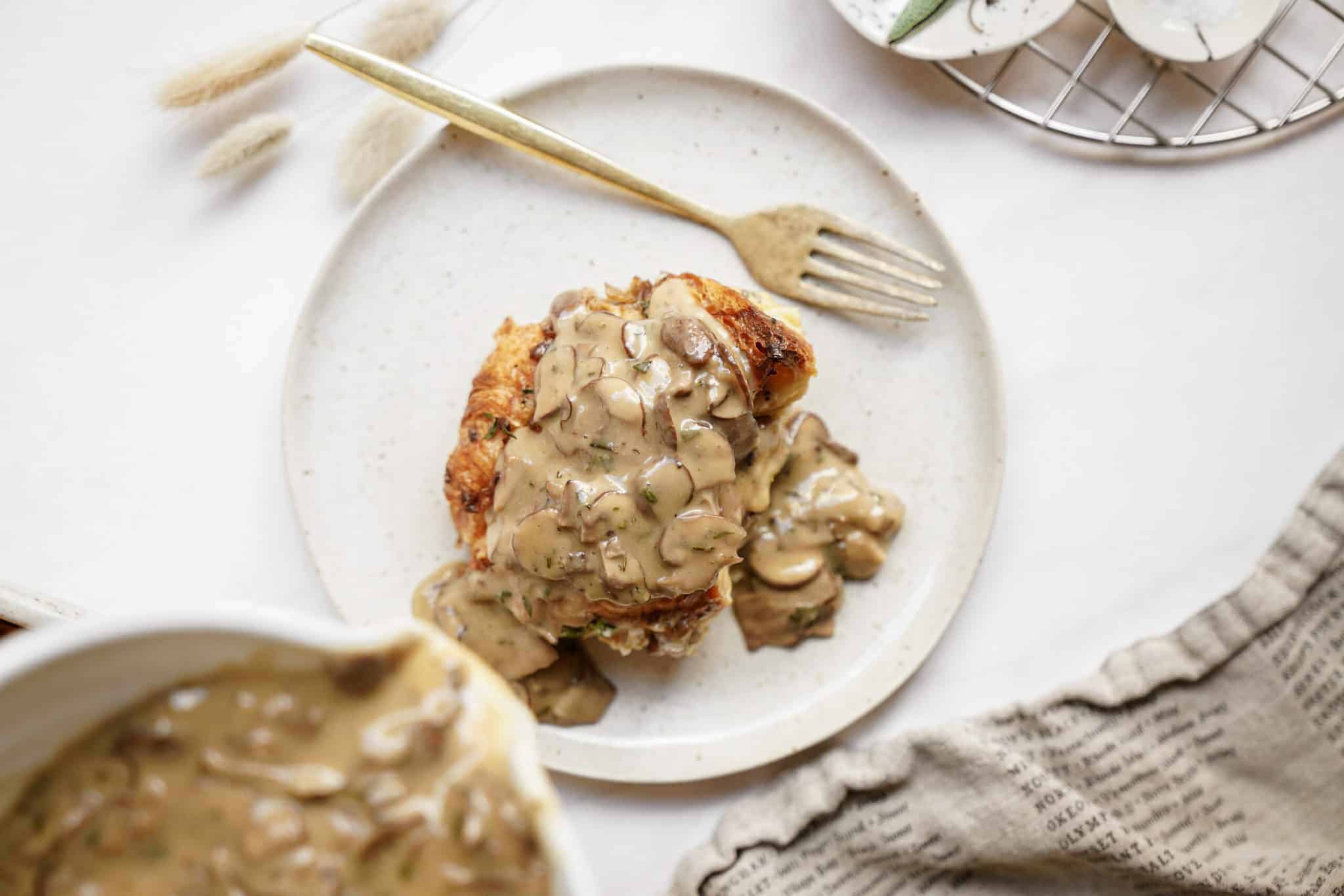 Mushroom gravy on top of veggies on a white plate. A how to make mushroom gravy guide