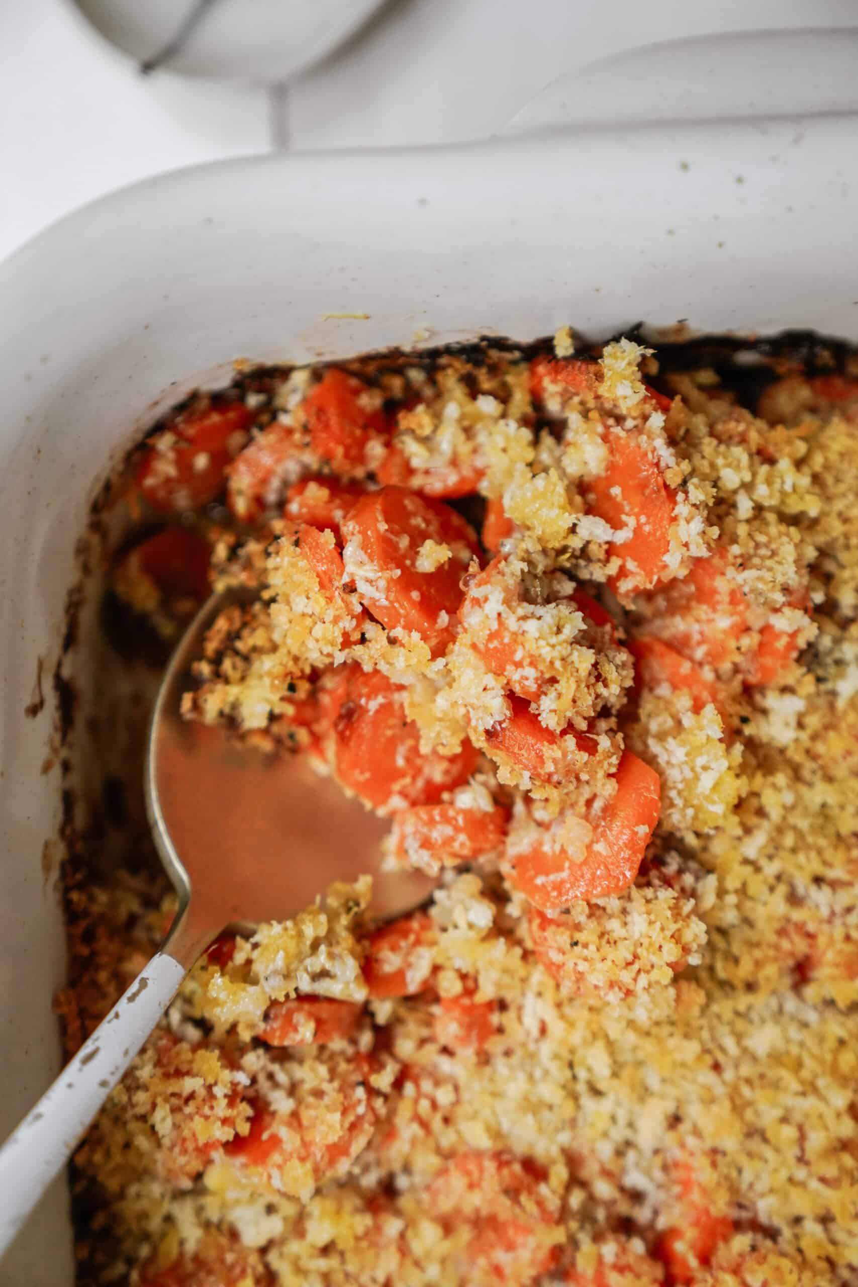 Baked carrots up close with serving spoon in a dish