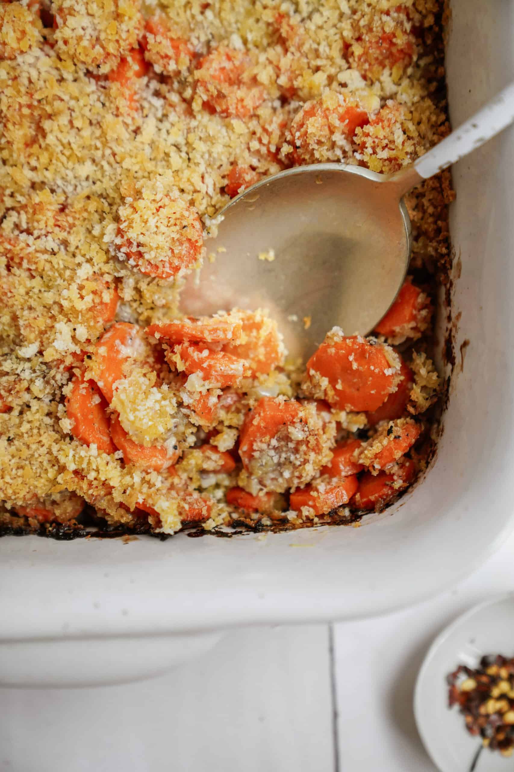 Baked carrots up close with serving spoon in a dish