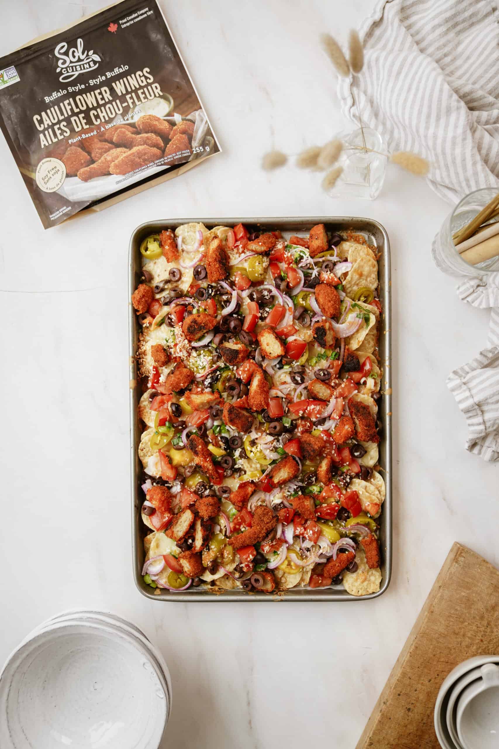 Cauliflower chicken wings next to a big tray of buffalo chicken nachos.