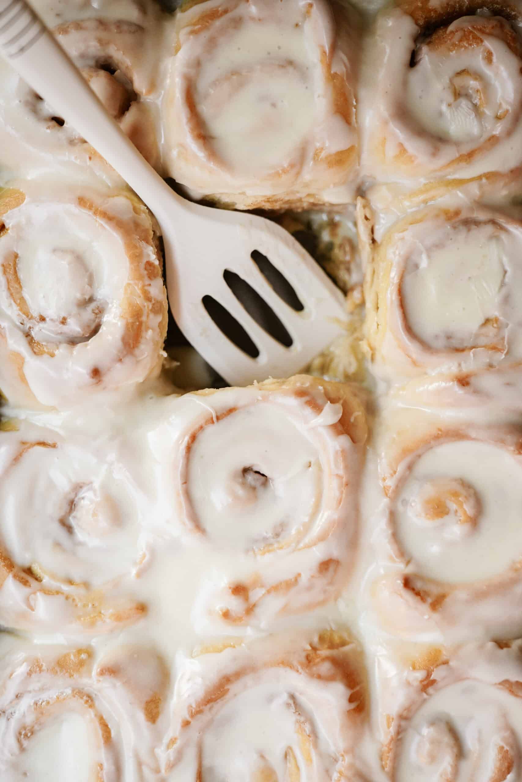 Eggnog cinnamon rolls in a casserole dish with a spatula