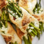 Golden puff pastries wrapped around asparagus spears and crumbled cheese, topped with a sprinkle of spices.