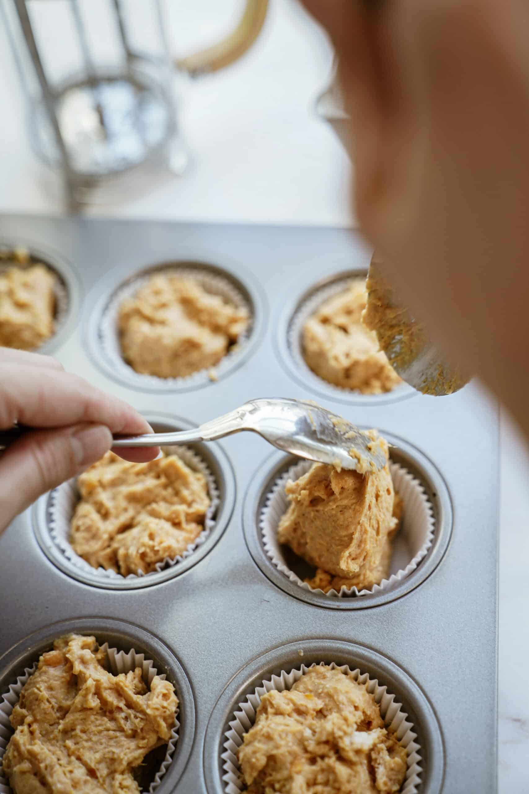 Muffin better being added to a muffin tin