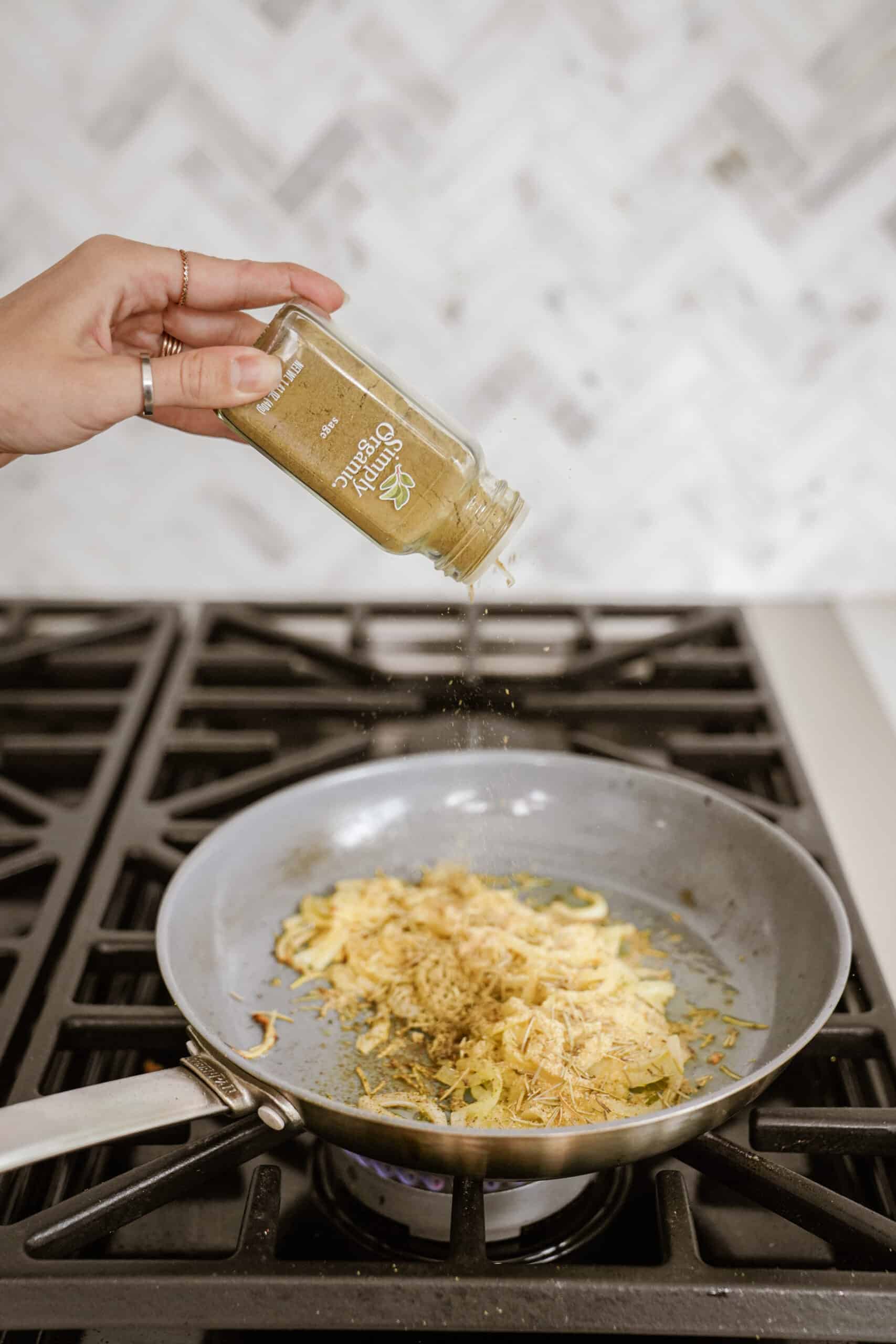 Spices being added to onions on a stove