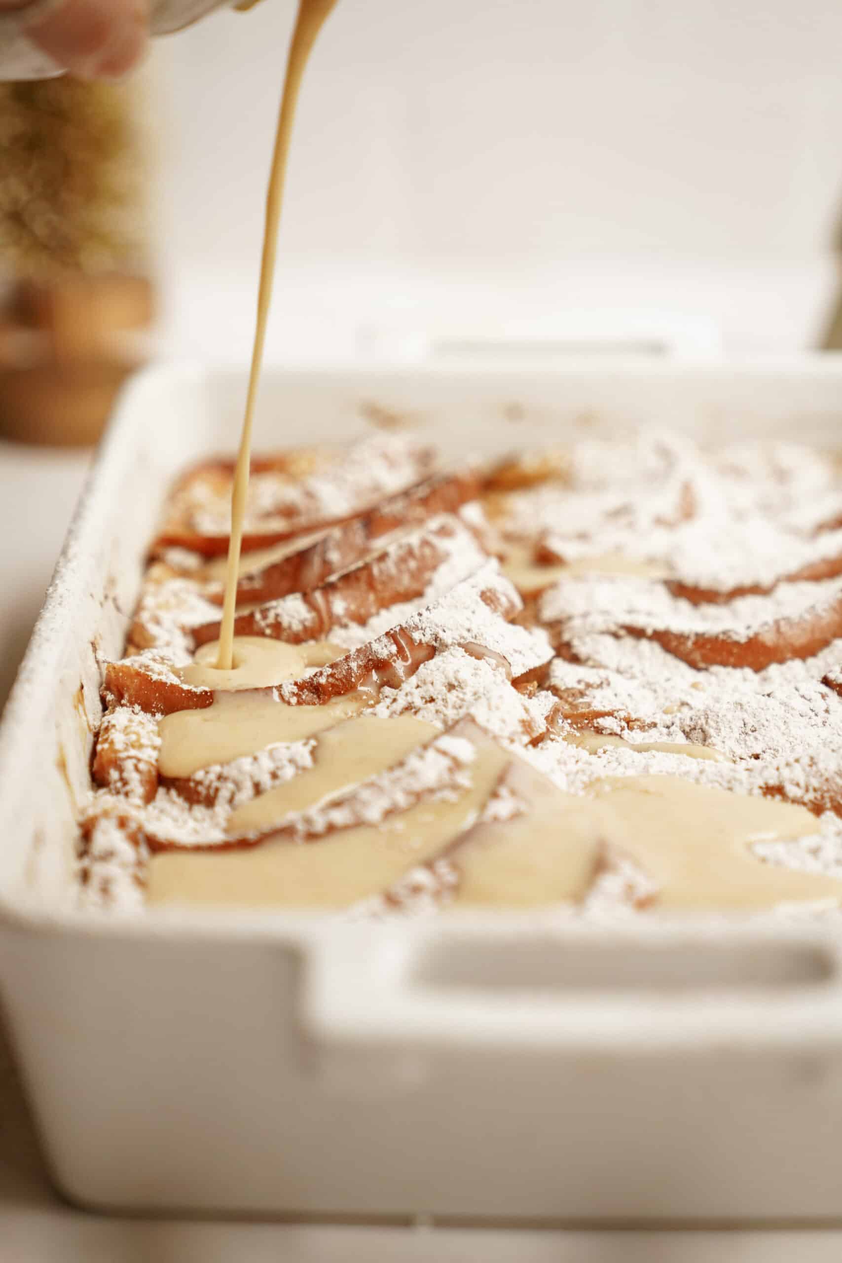 Baked French Toast Recipe in casserole dish with sauce being poured ontop