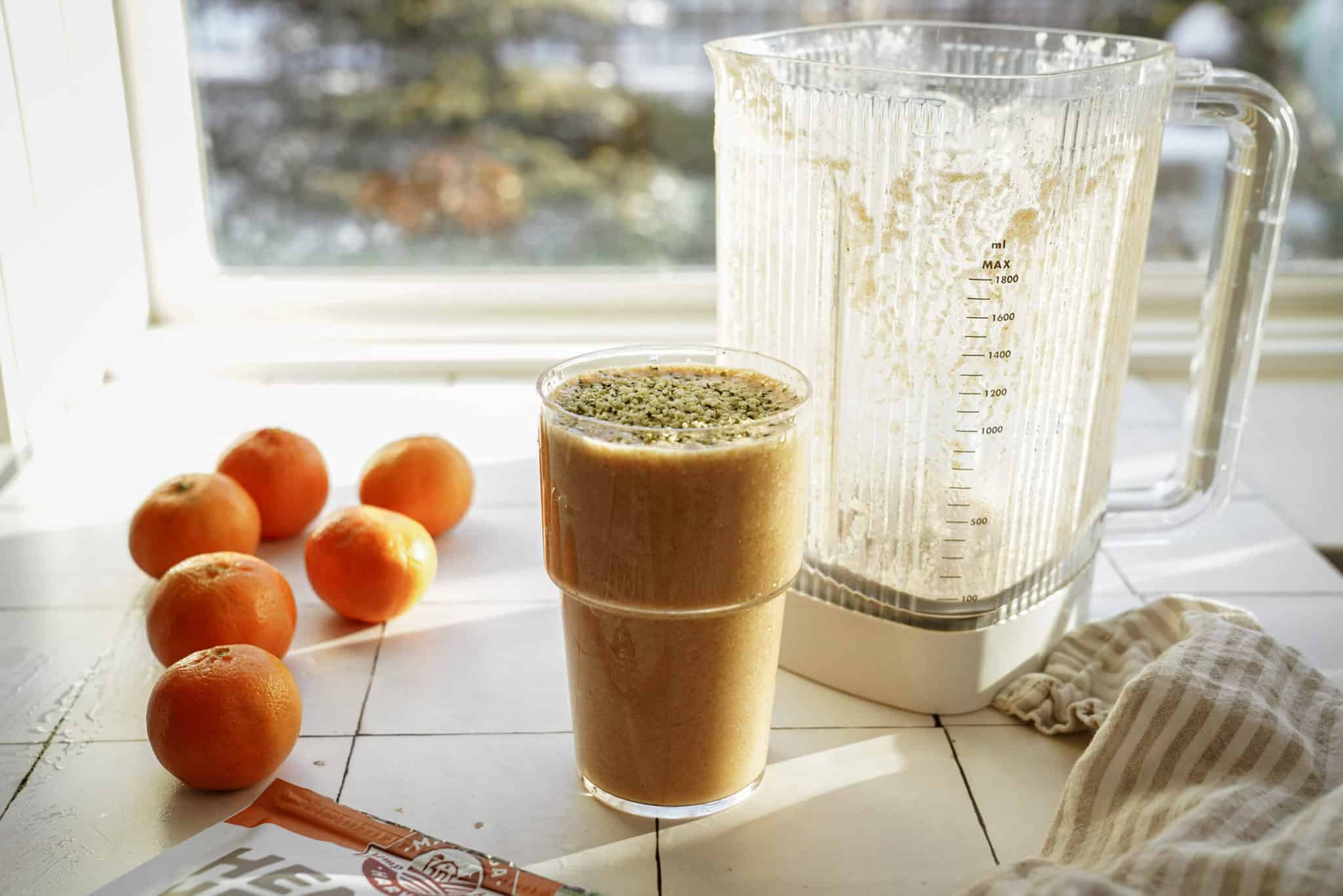 carrot cake smoothie next to fresh oranges and a blender