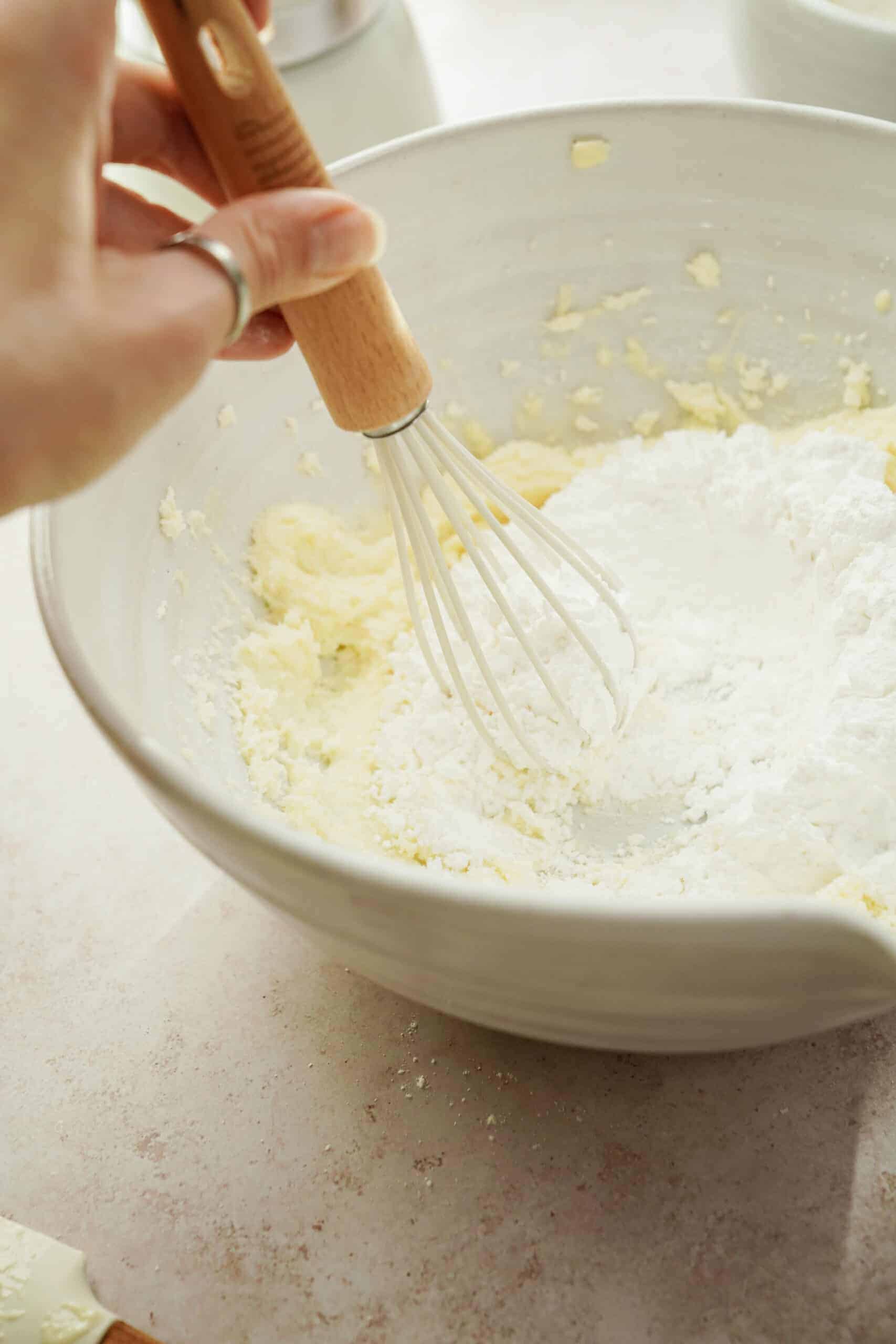Icing sugar being added into wet ingredients with a whisk 