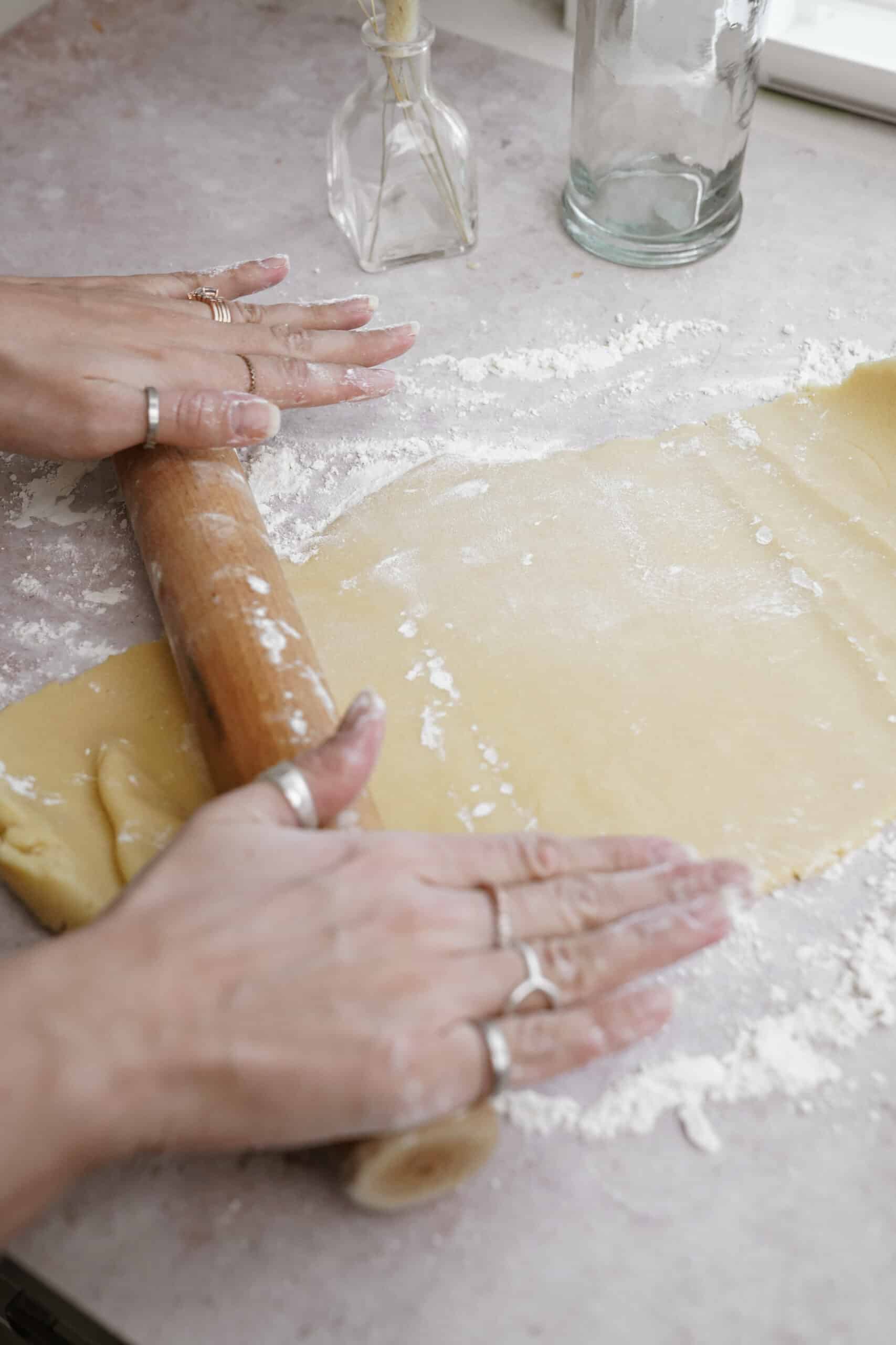 Dough being rolled on floured counter for holiday sugar cookies