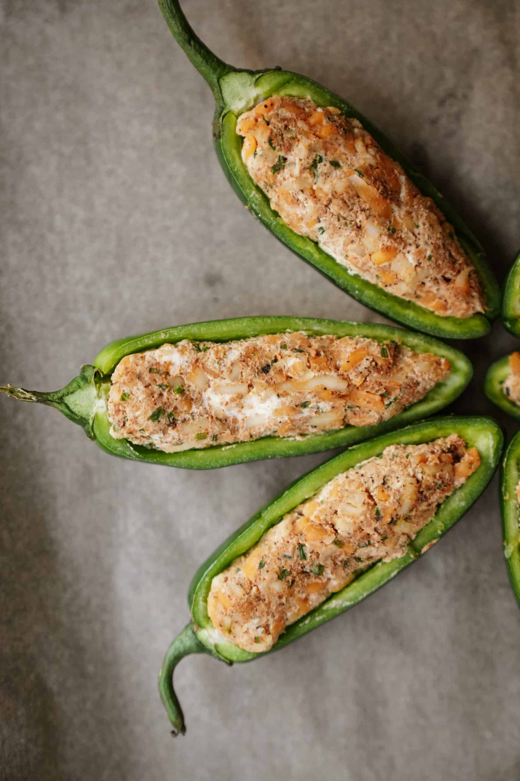 Three jalapeno poppers laying on a baking tray