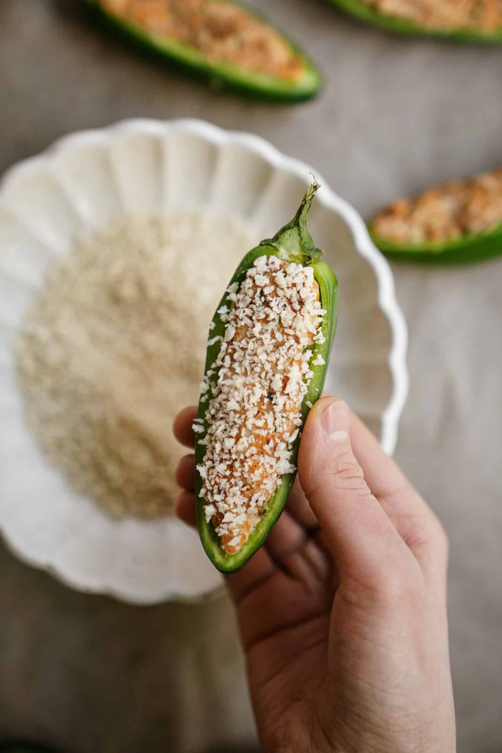Dipping pepper into breadcrumbs, a step in how to make jalapeno poppers