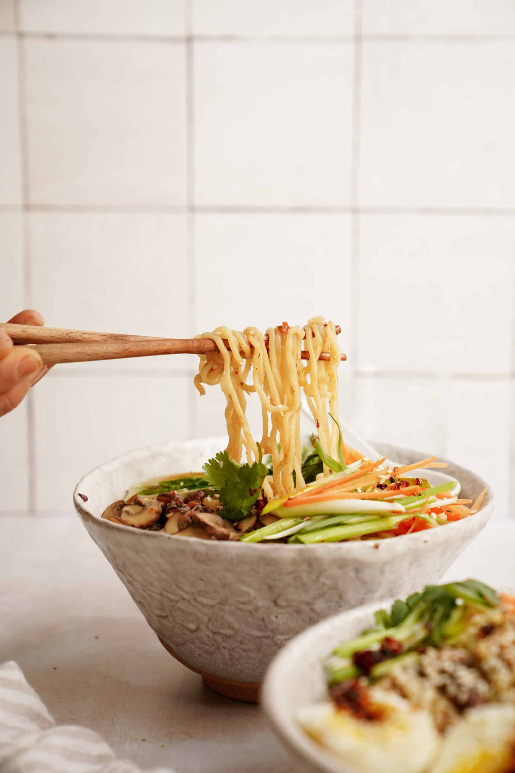 Side view of mushroom ramen with chopsticks taking noodles out of bowl