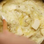 roasted garlic mashed potatoes being stirred in a big bowl