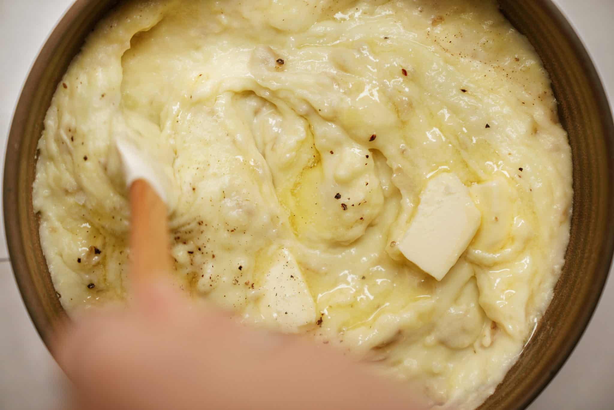 roasted garlic mashed potatoes being stirred in a big bowl