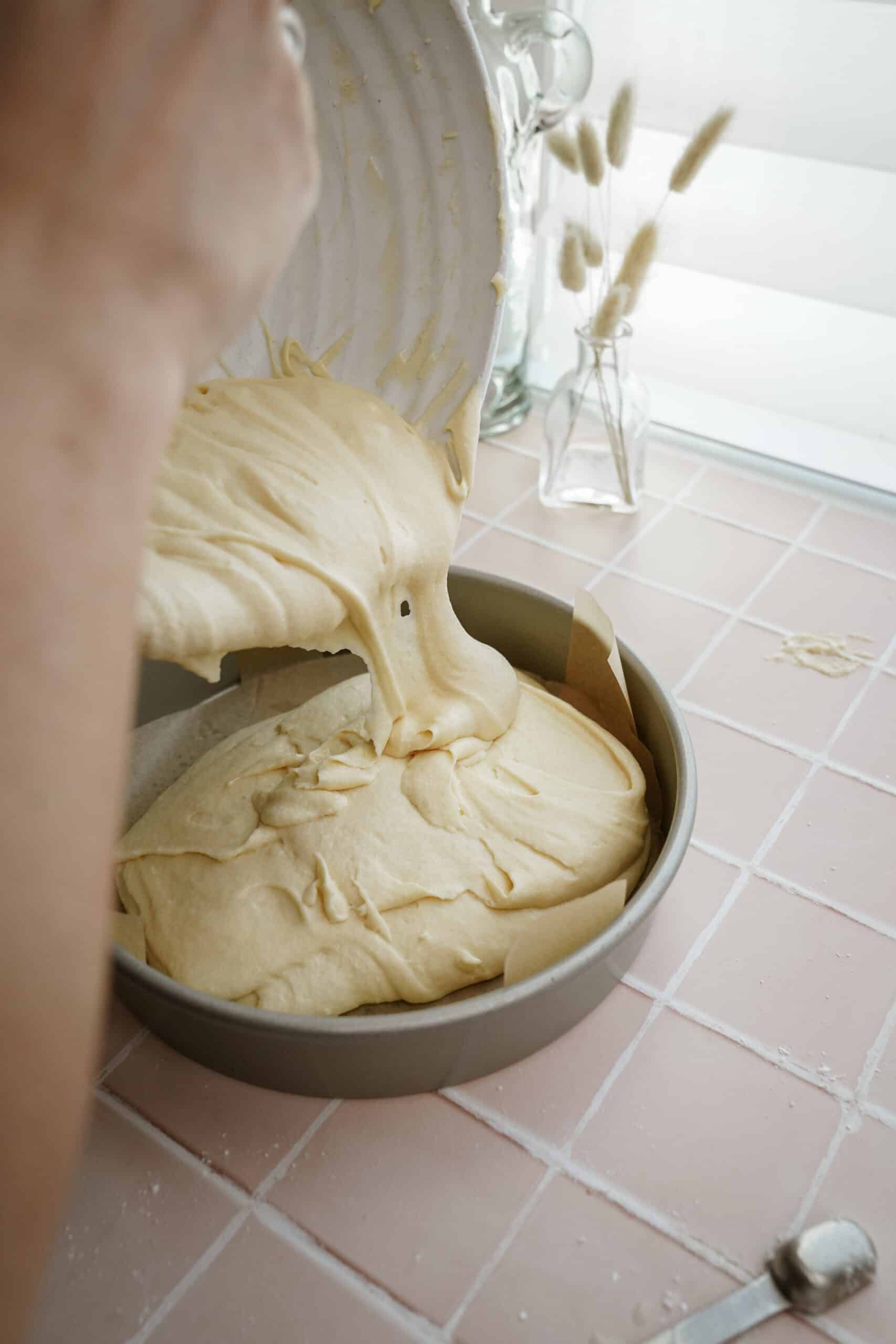 Vanilla cake batter being added to a cake pan
