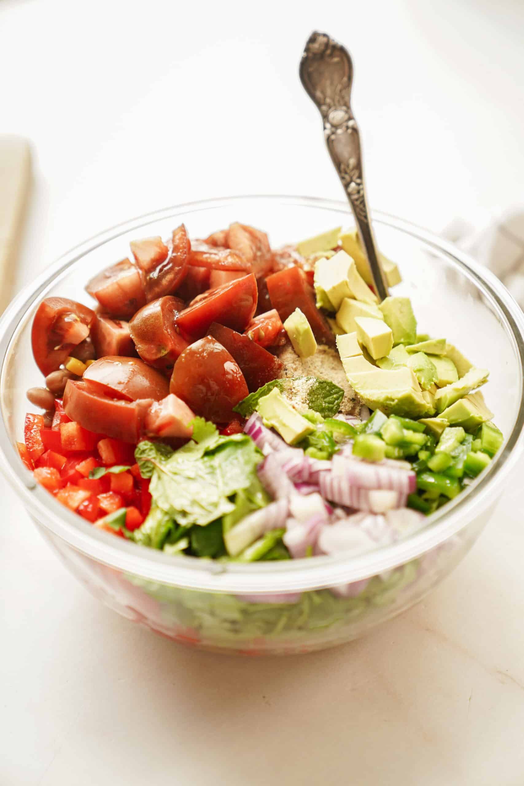 Fresh ingredients for bean salad in a bowl with a spoon
