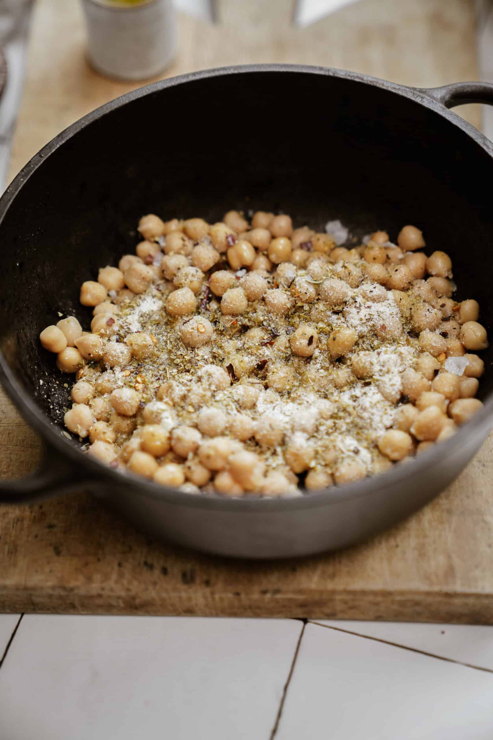 Seasoning being added to chickpeas in a pot