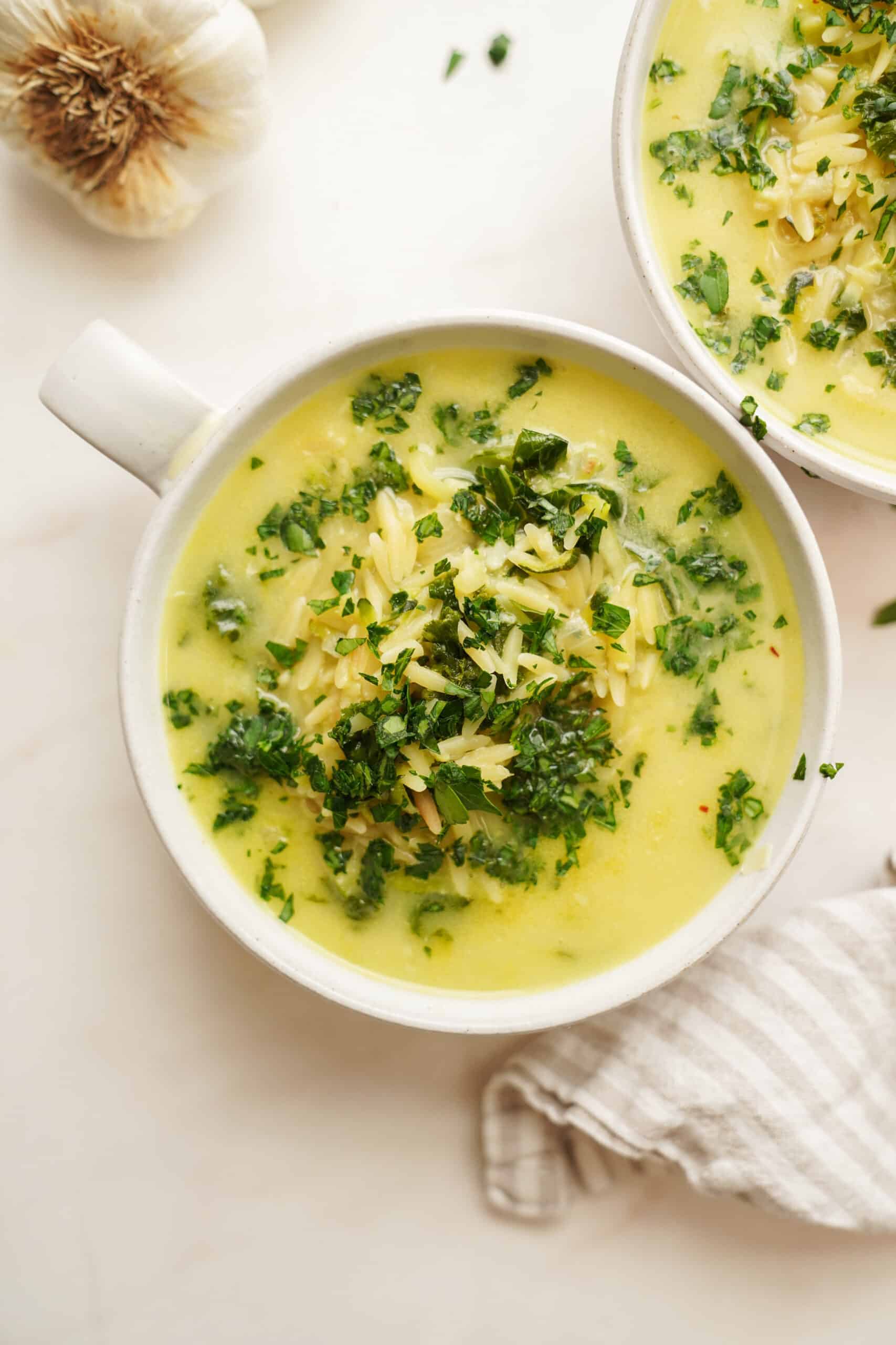 Lemon orzo soup in a white bowl with a handle