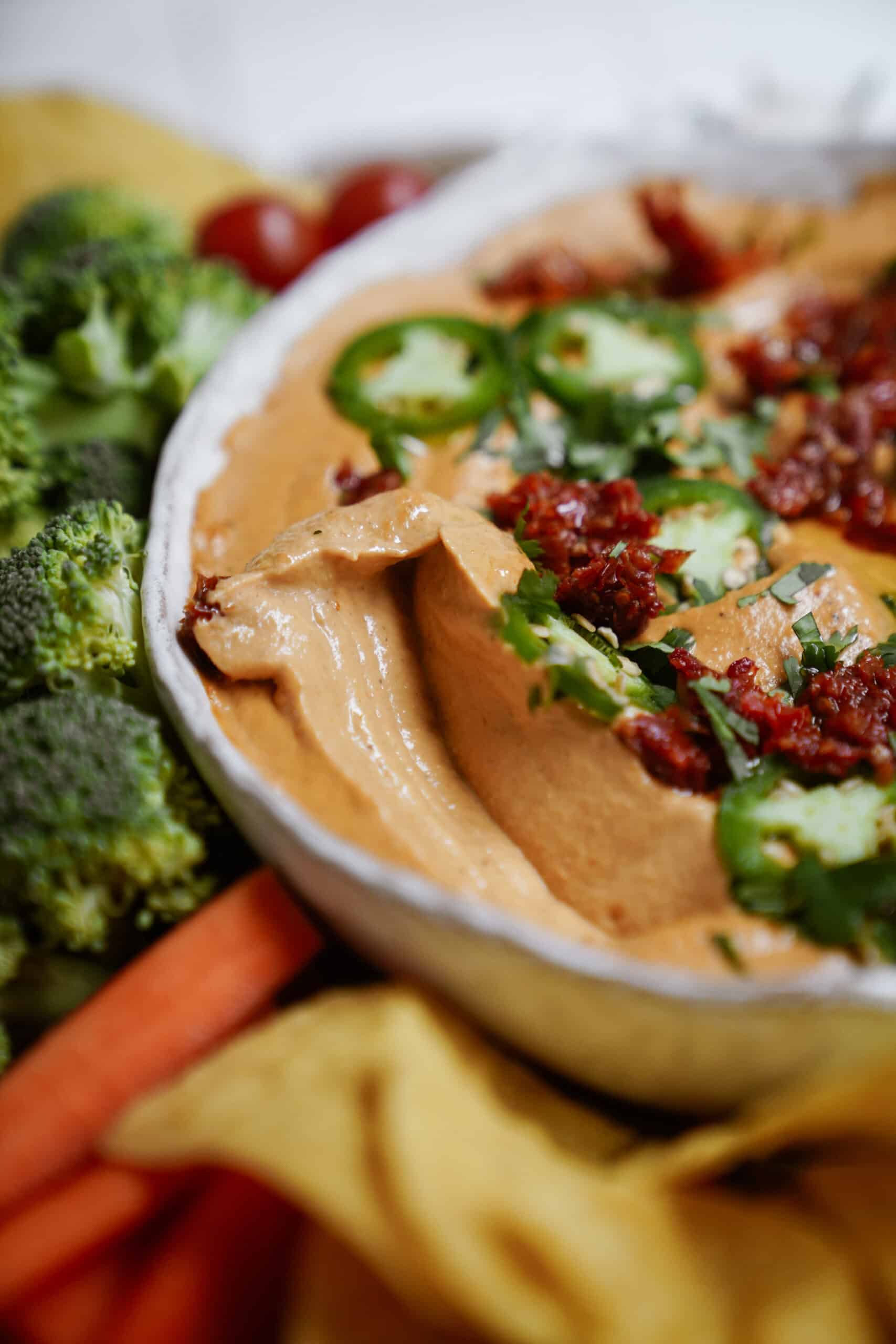Close-up of queso sauce recipe in a bowl surrounded by veggies