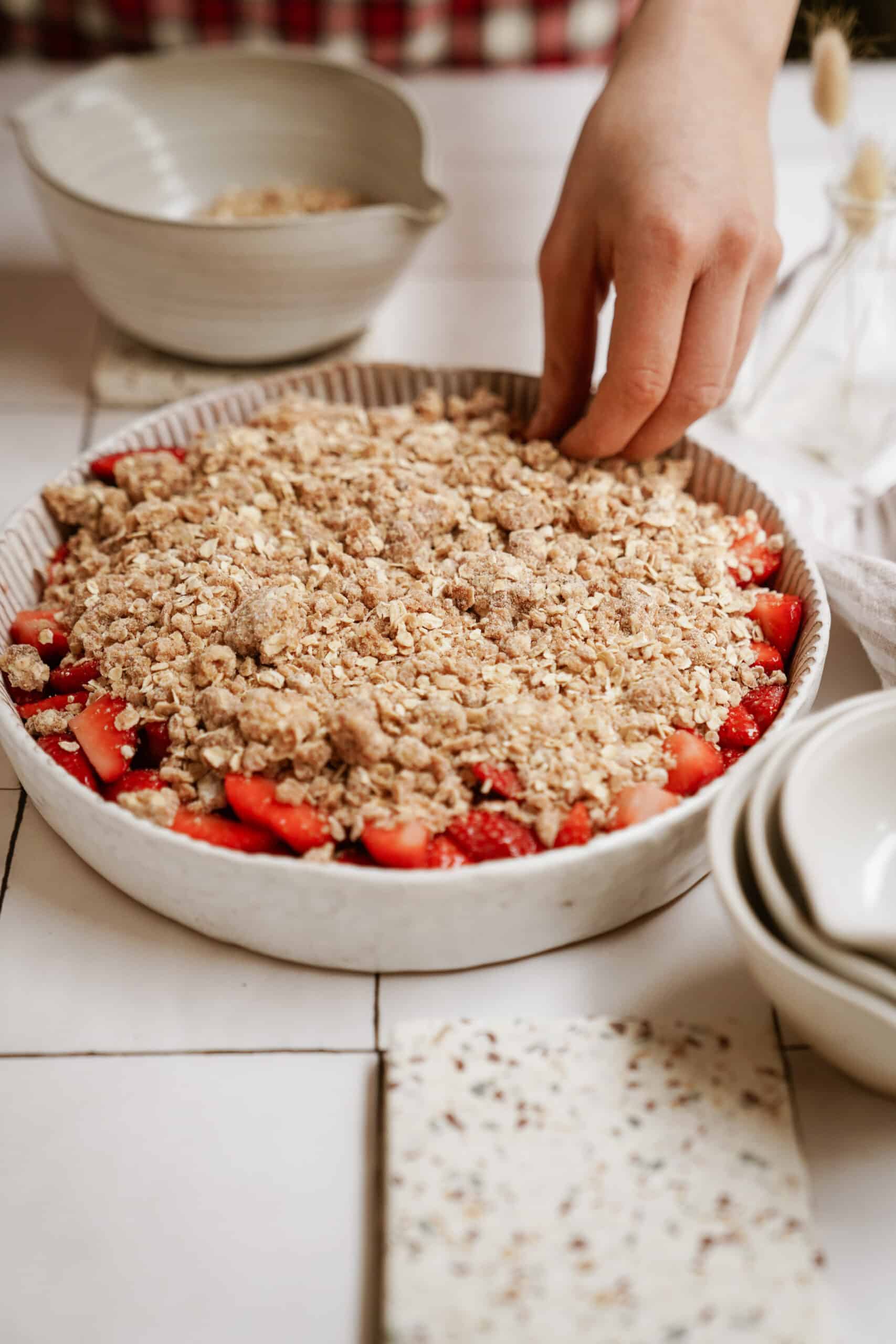 Adding crumble on top of strawberry mixture
