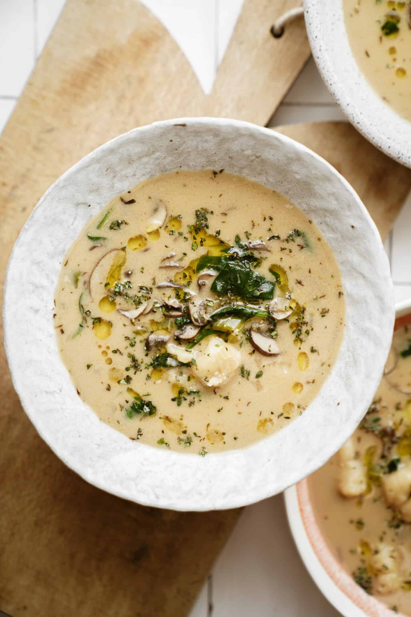 Creamy soup topped with a drizzle of oil and fresh green veggies