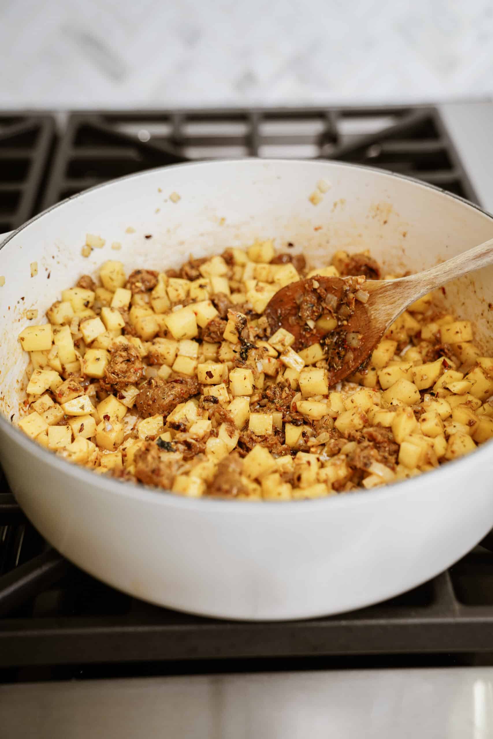 Sausage, onion, and potato cooking in a pot on a stove