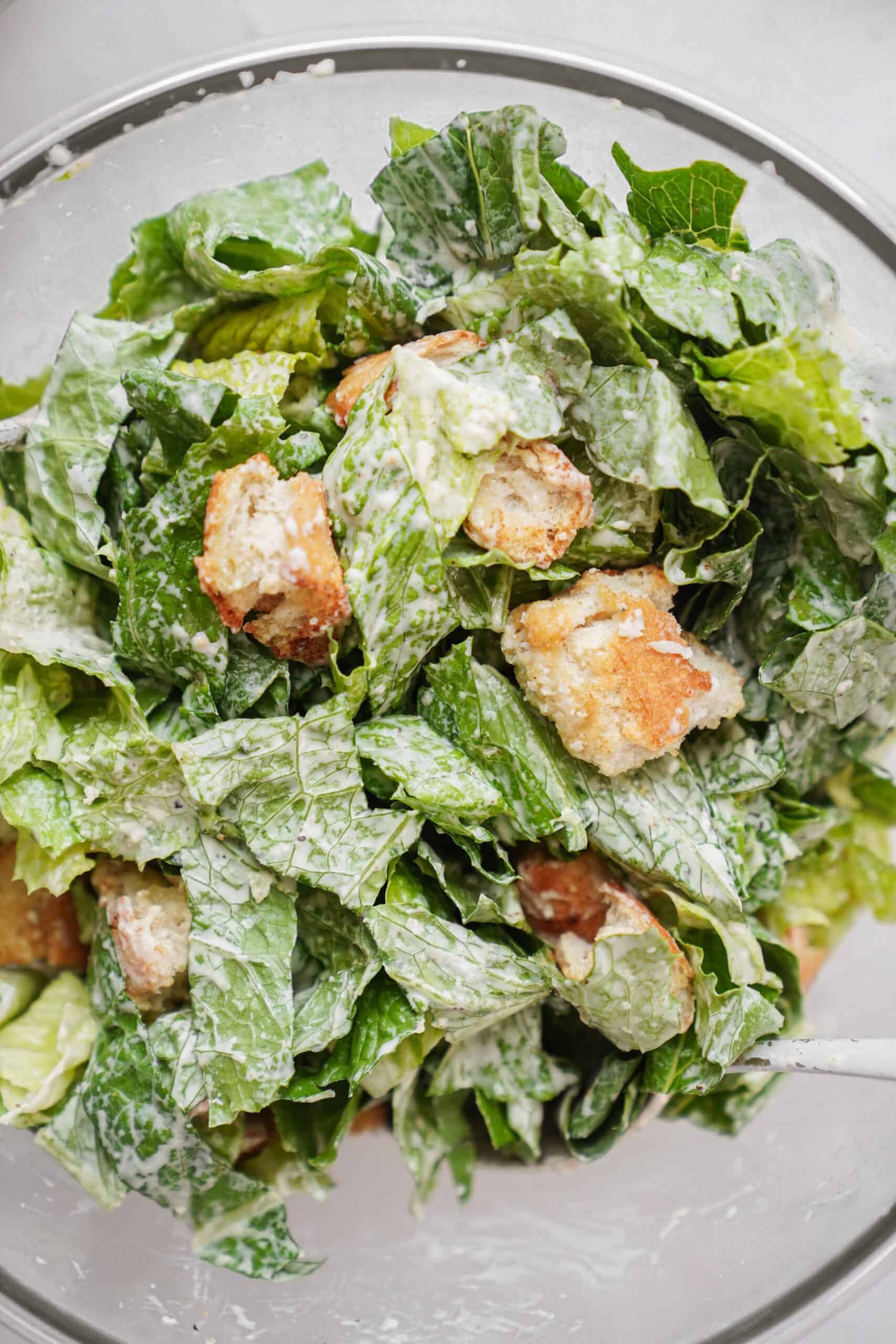 Caesar salad dressing recipe on top of a fresh lettuce with crutons