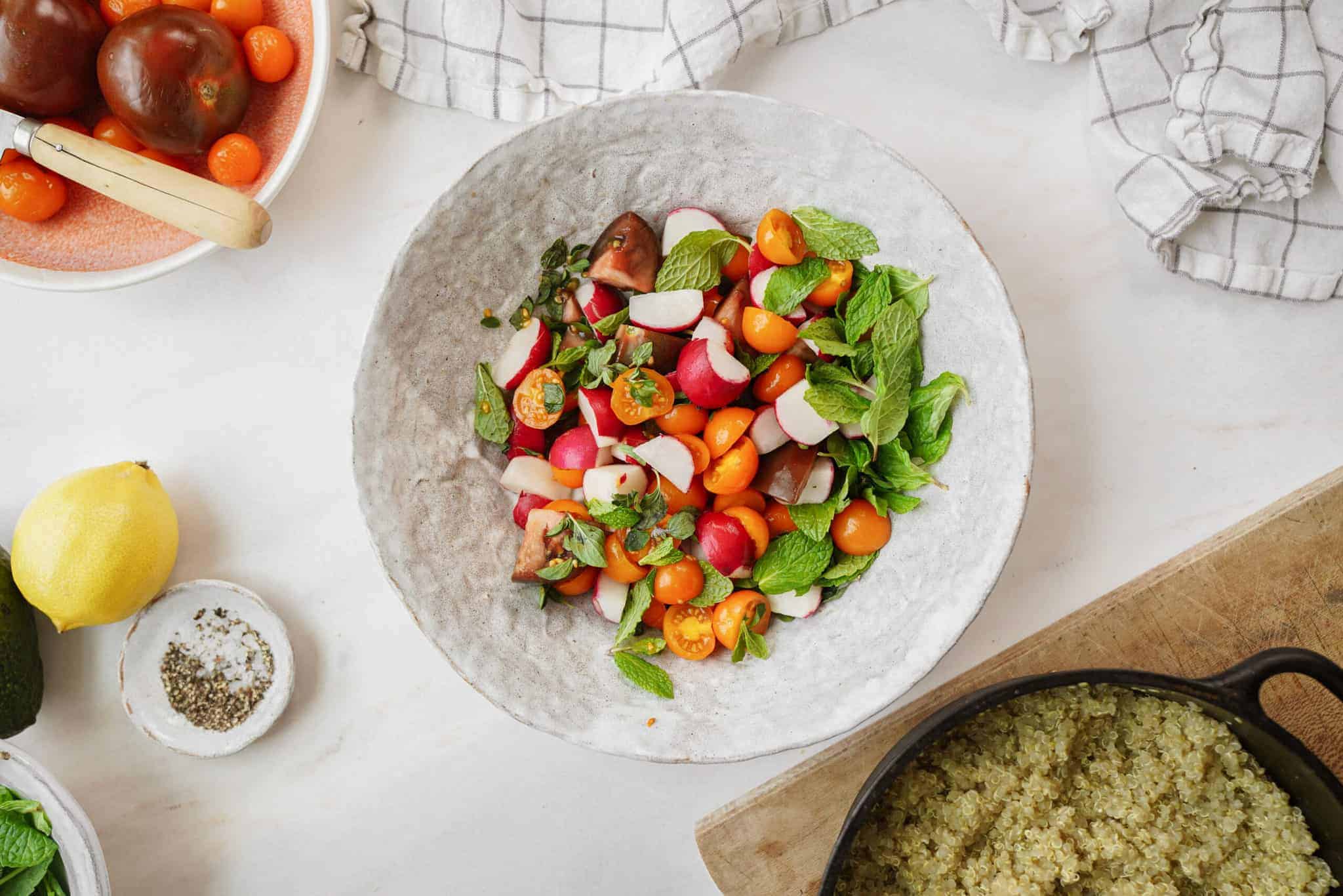 Fresh ingredients for Mediterranean quinoa salad in a white bowl