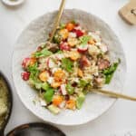 Mediterranean quinoa salad in a bowl with serving spoons