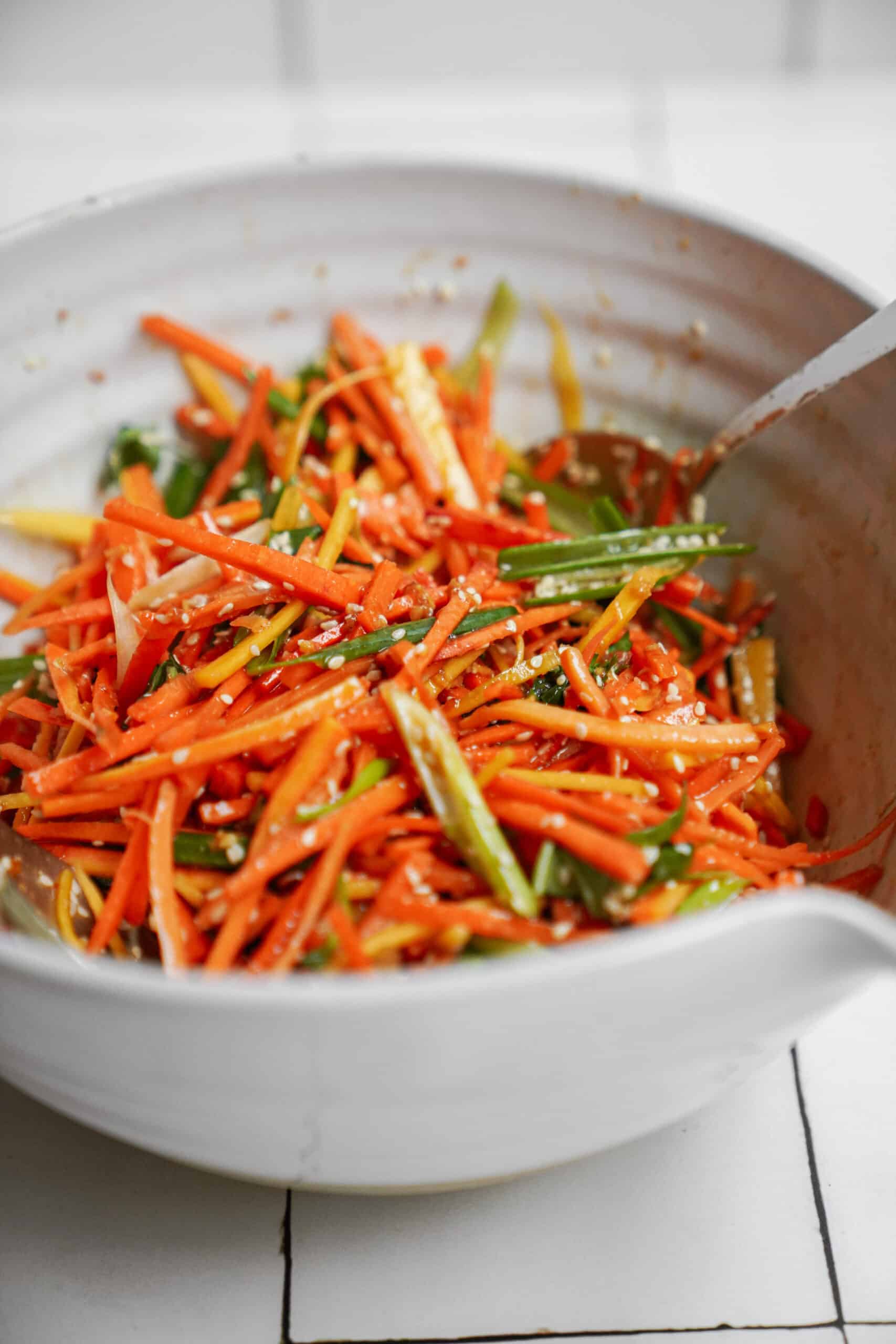 Vegan Carrot Salad in a white bowl with a spoon 