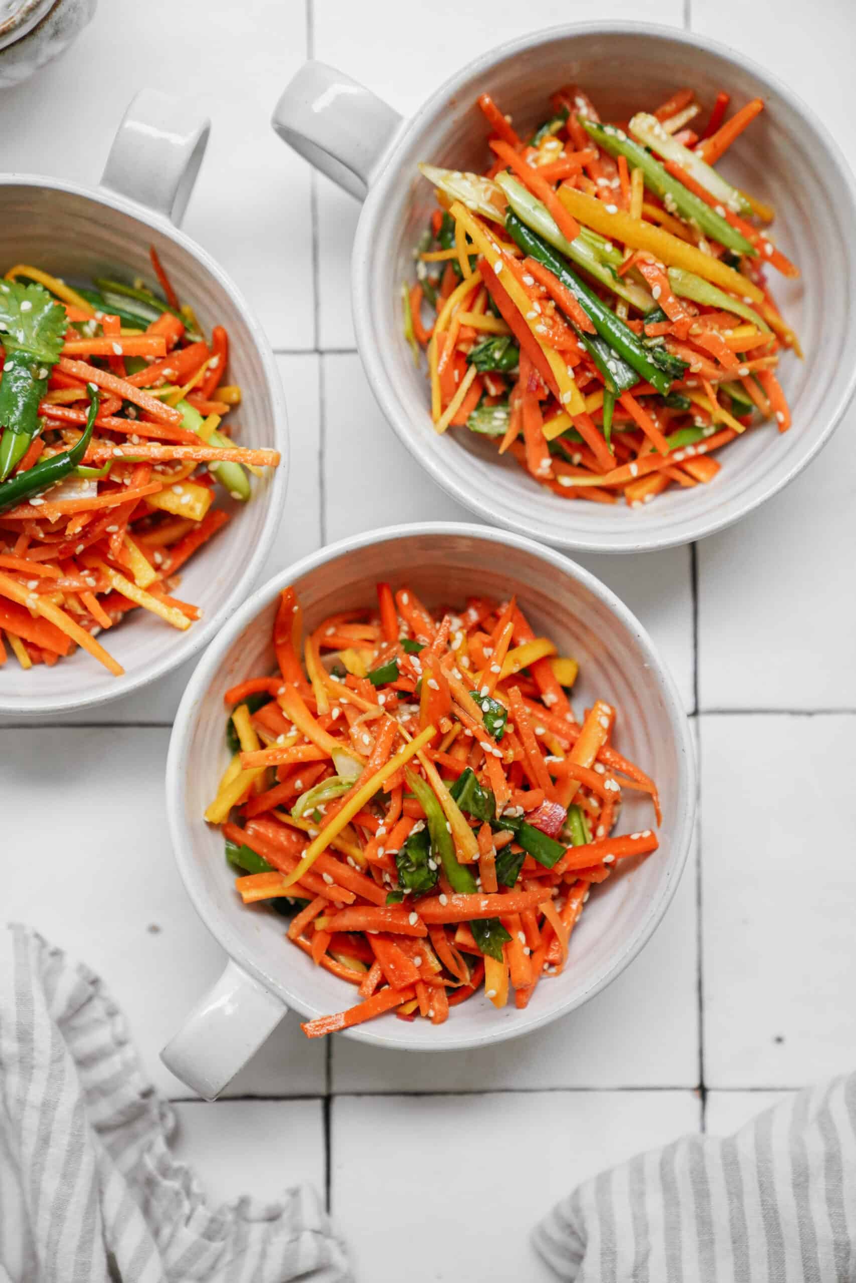 Fresh carrot salad in white bowls on a counter