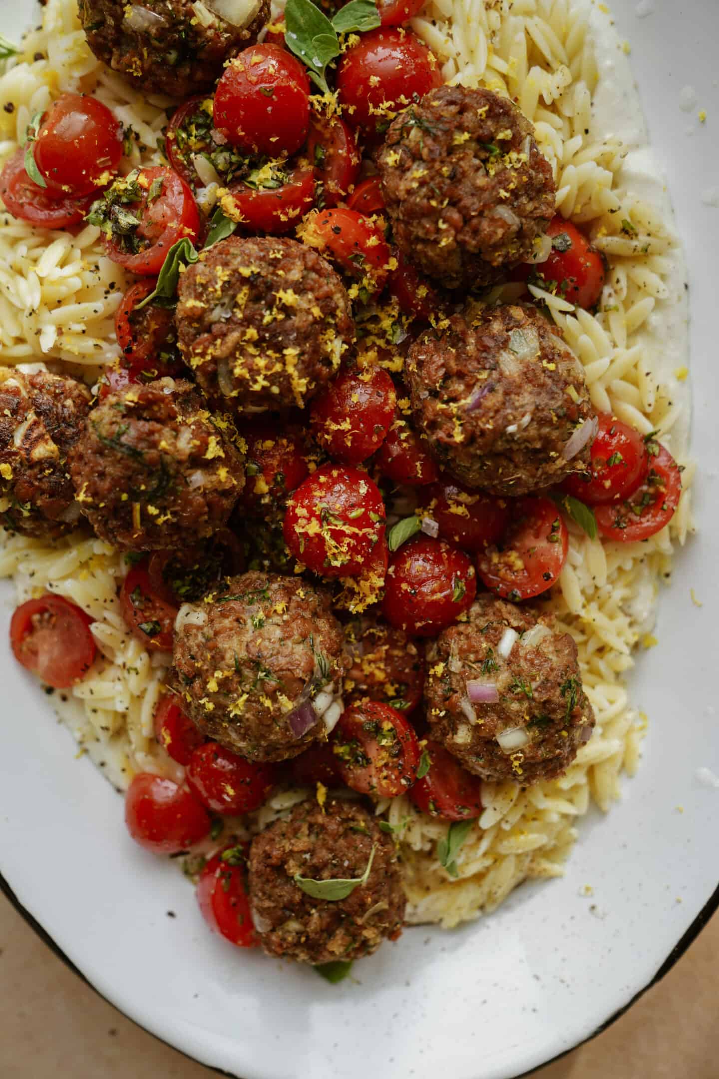 Vegan Greek Meatballs close-up on a white serving dish with creamy orzo