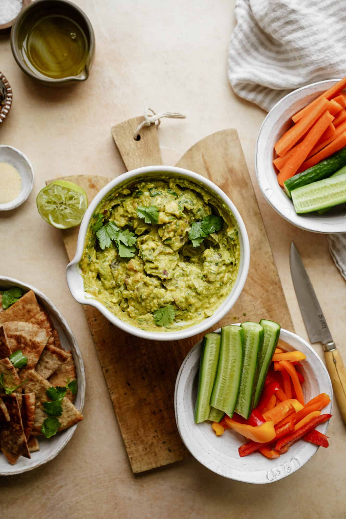 Guacamole on a cutting board surrounded by fresh veggies