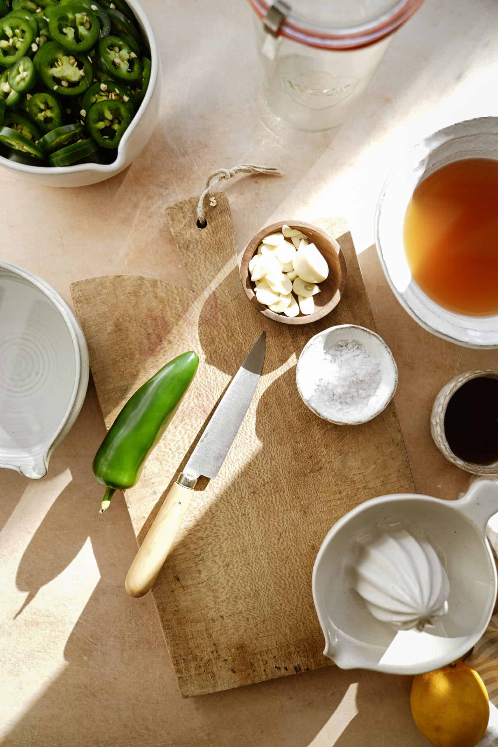 Ingredients for pickled jalapenos on counter with cutting board