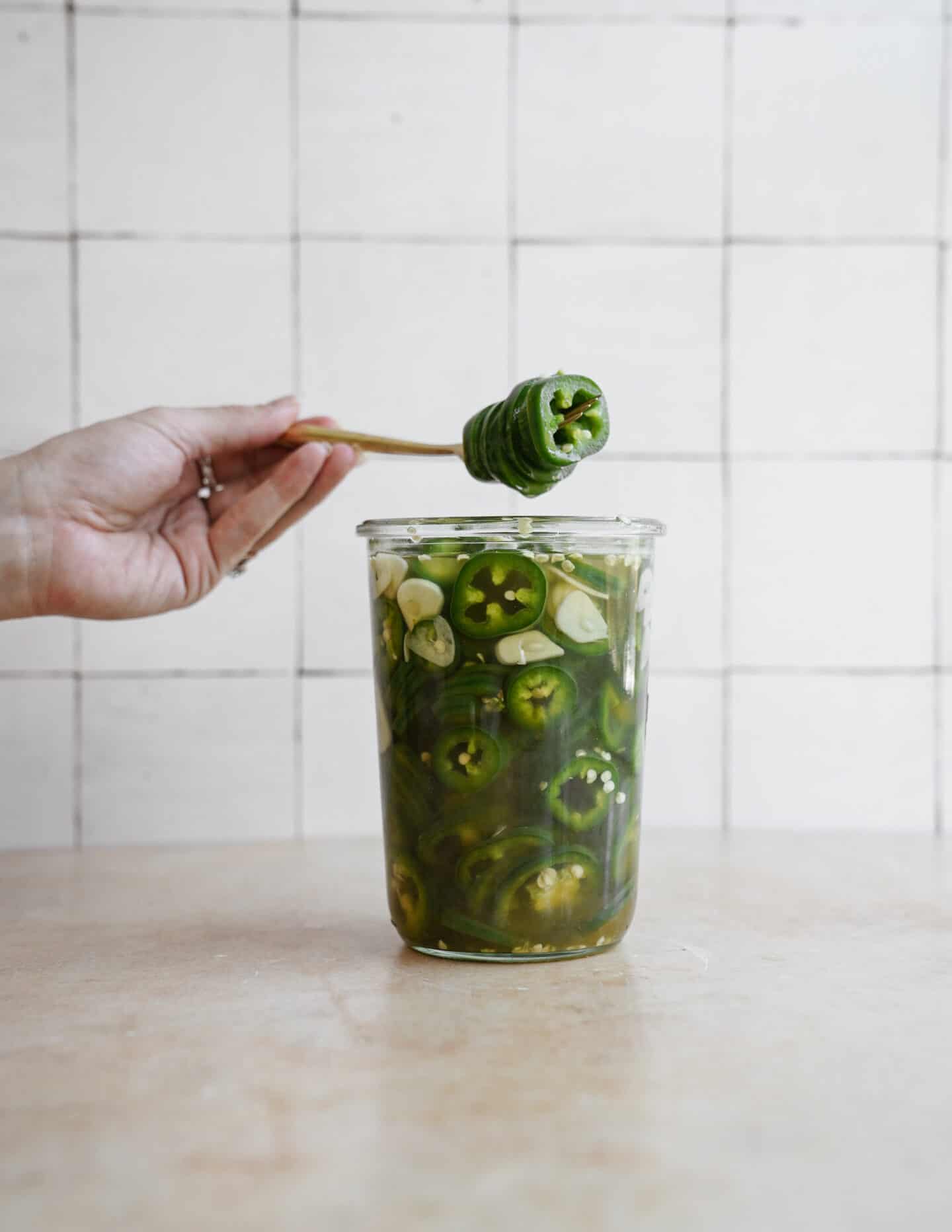 Fork picking pickled jalapenos out of a mason jar