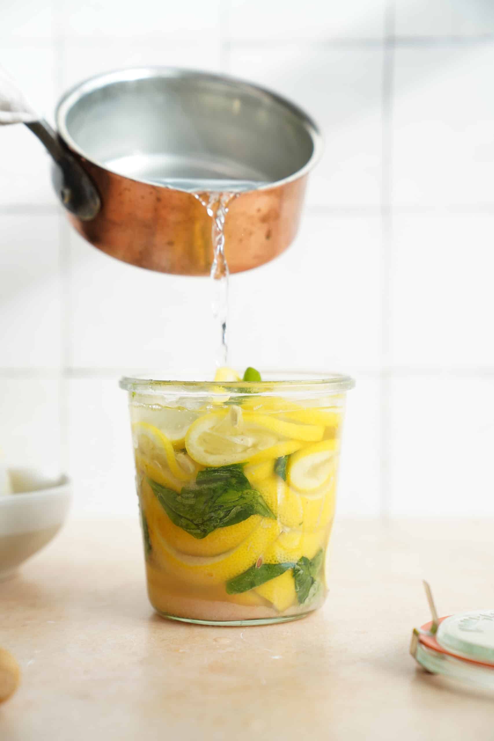 Water pouring into jar with lemon and basil