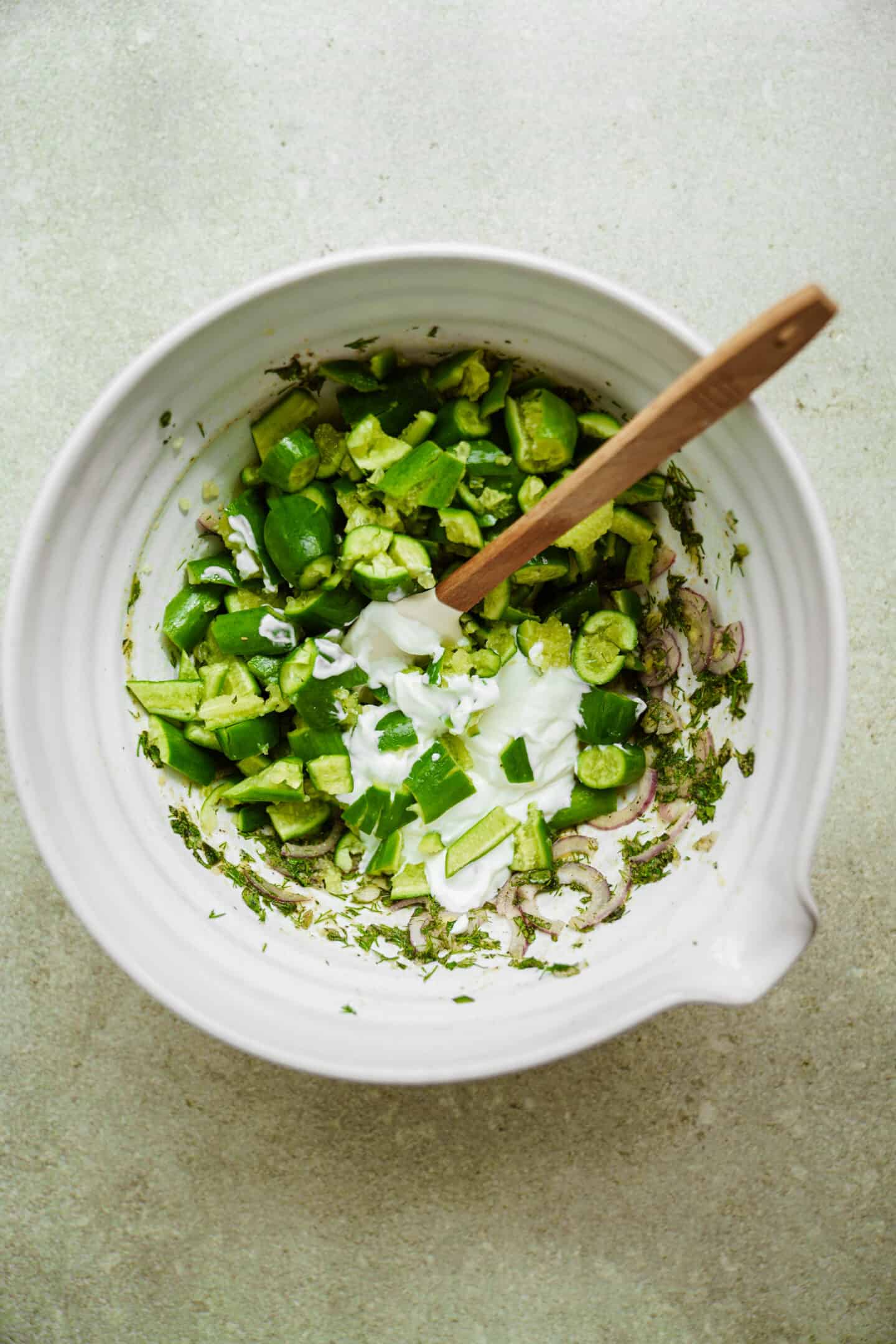 Mixing up creamy cucumber salad in a bowl