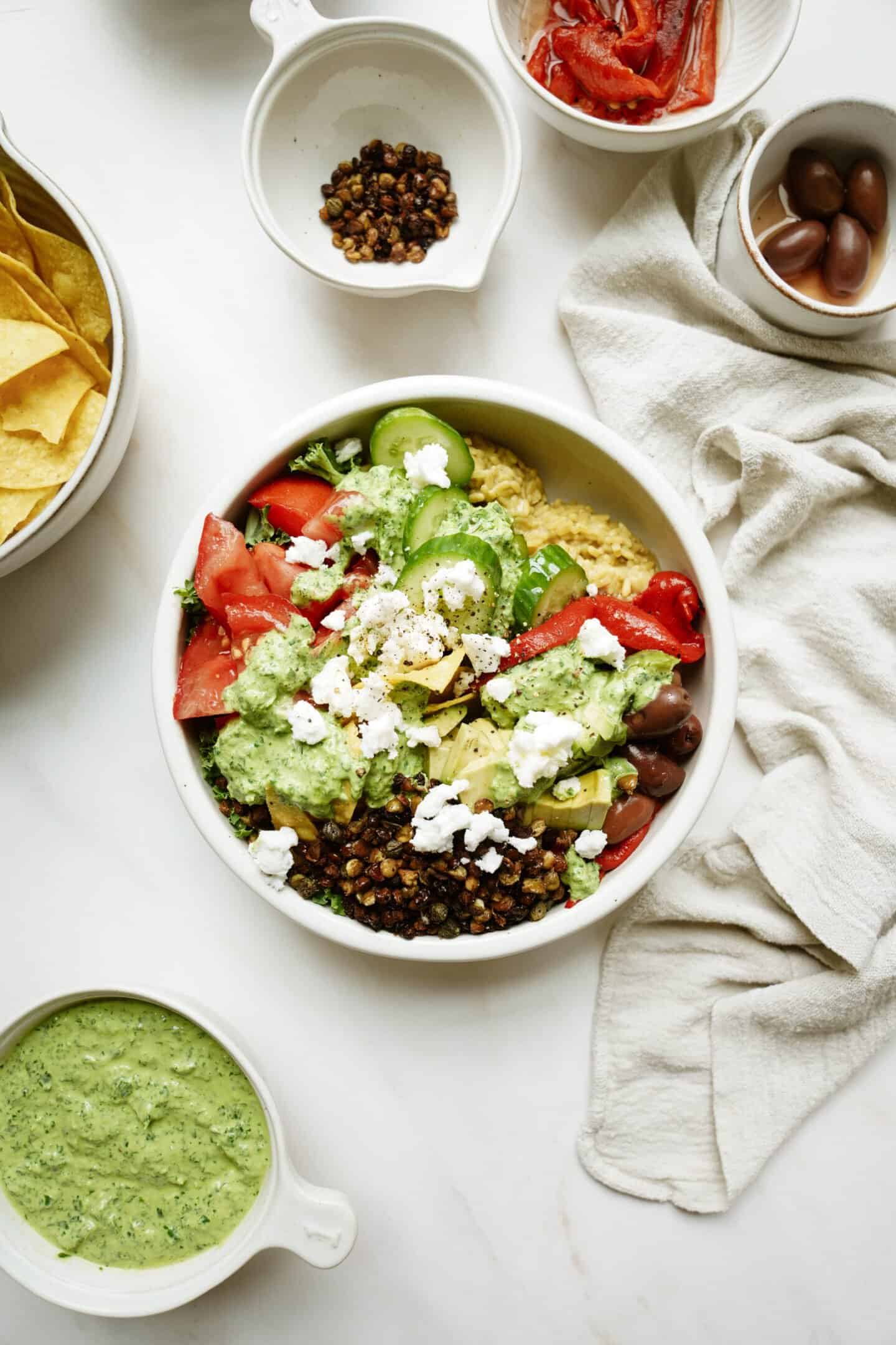 Mediterranean rice bowl on counter in white bowl surrounded by ingredients