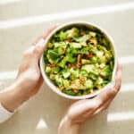 Hands holding a broccoli salad